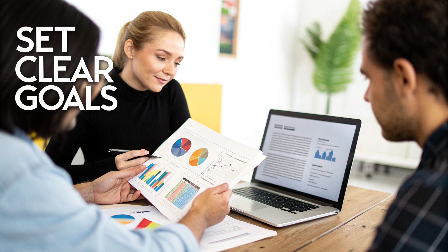 Three professionals analyze charts and data on a laptop, focusing on goal setting.