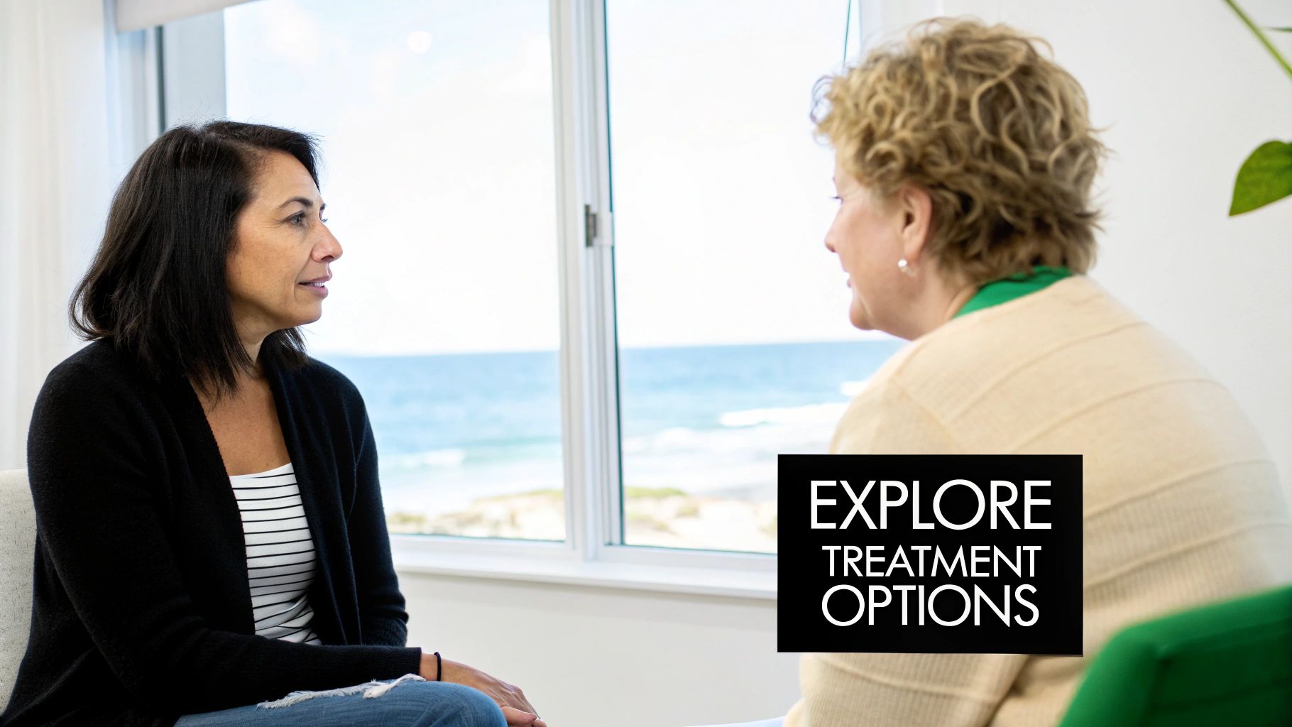 Two women in a counseling session, discussing treatment options with the ocean view in background.