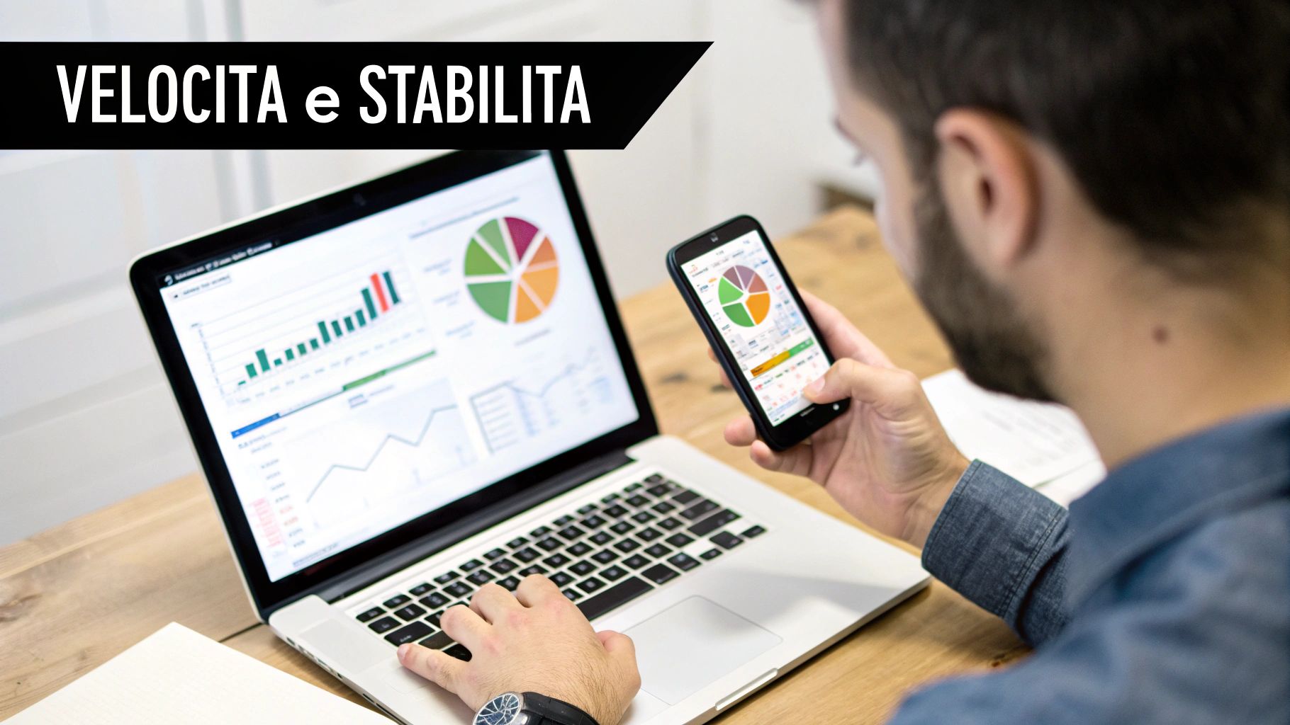 Un uomo analizza dati aziendali su laptop e smartphone, visualizzando grafici e report per efficienza e stabilità.