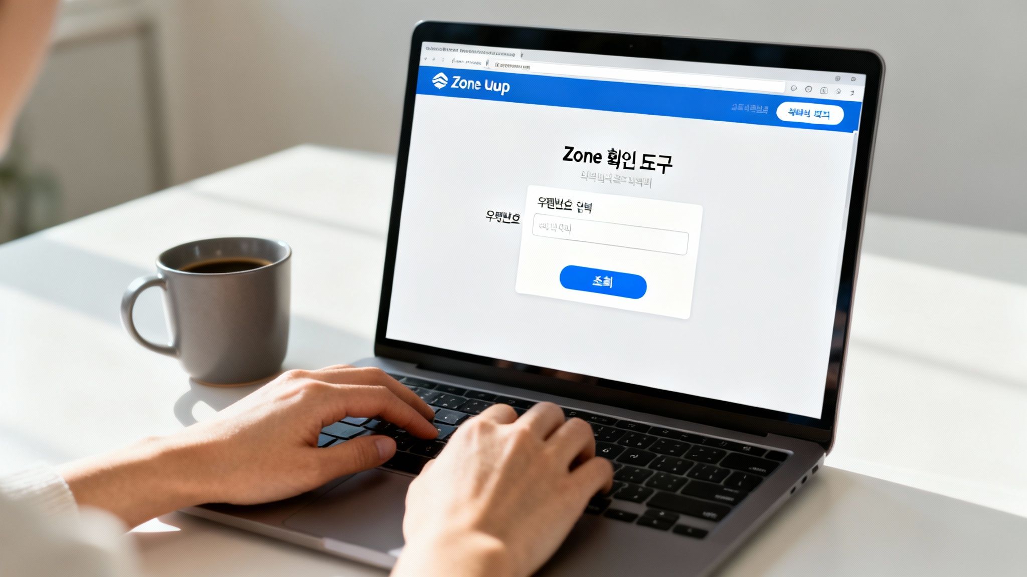 밝은 테이블에 놓인 노트북으로 Zone Uup 웹사이트에서 우편번호를 조회하는 손과 커피 한 잔.