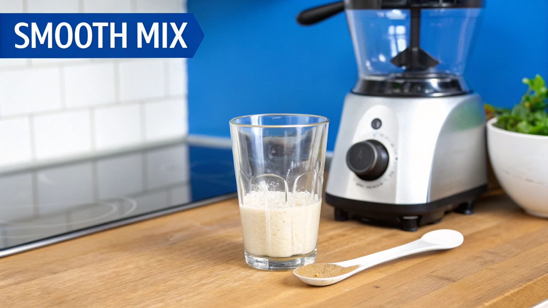 A glass with a creamy drink, a spoon with powder, and a blender on a wooden counter, ready for a smooth mix.