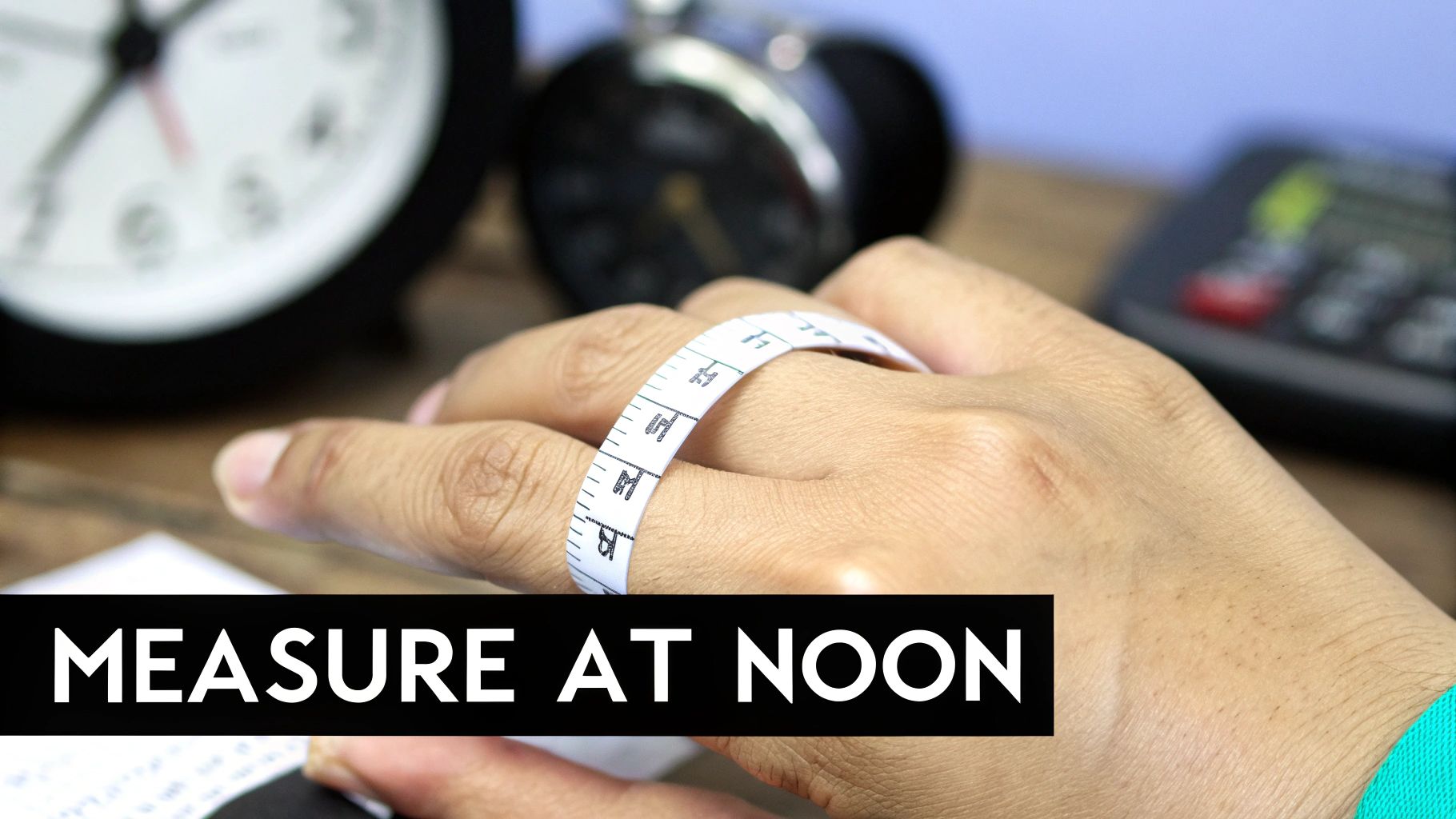 A hand with a white measuring tape wrapped around a finger, with clocks in the background and 'MEASURE AT NOON' text.