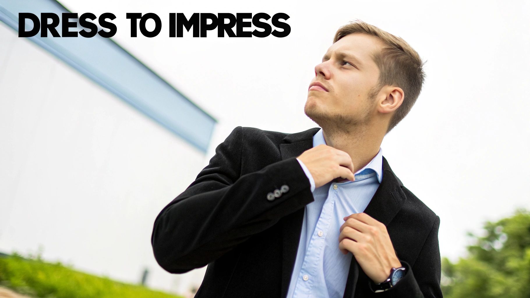 Um jovem vestindo um blazer preto e camisa azul clara ajustando a gola, olhando para cima.