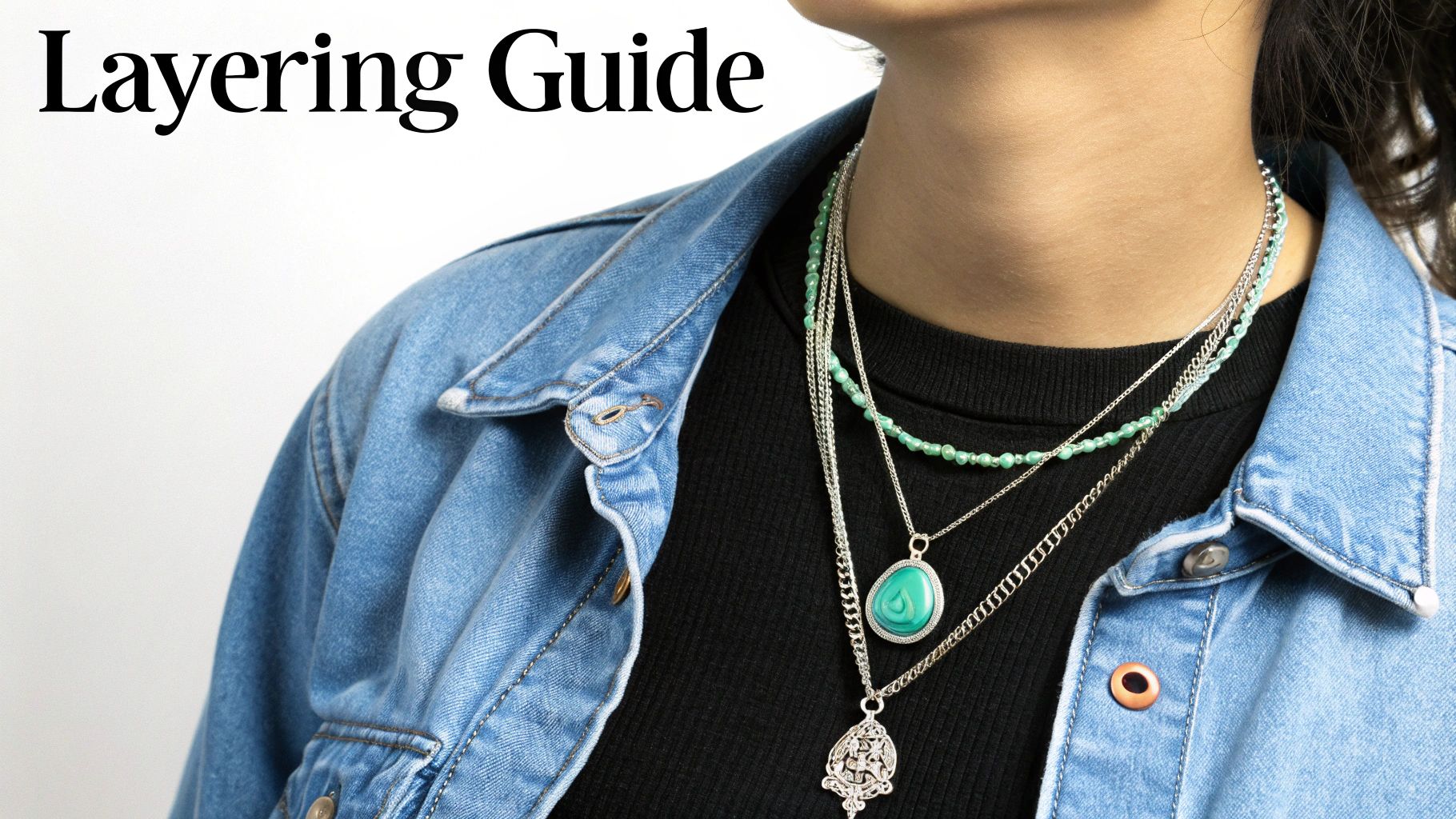 Close-up of a person wearing a denim jacket with multiple layered silver and green beaded necklaces.