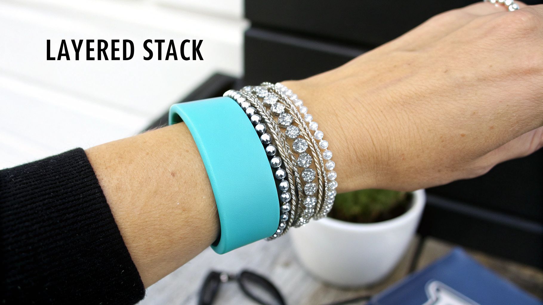 Close-up of a wrist adorned with a wide turquoise cuff and multiple sparkling layered bracelets.