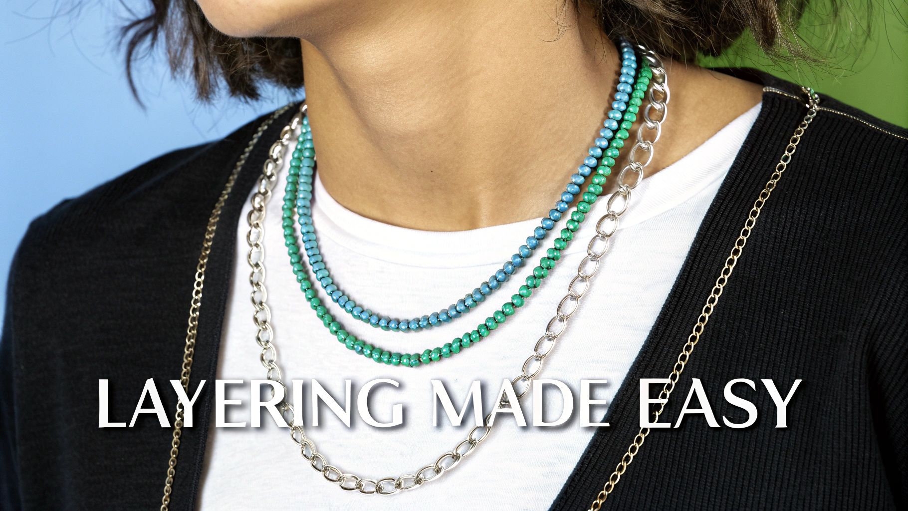 A person wearing multiple layered necklaces, including colorful beaded and metal chain designs, demonstrating easy styling.