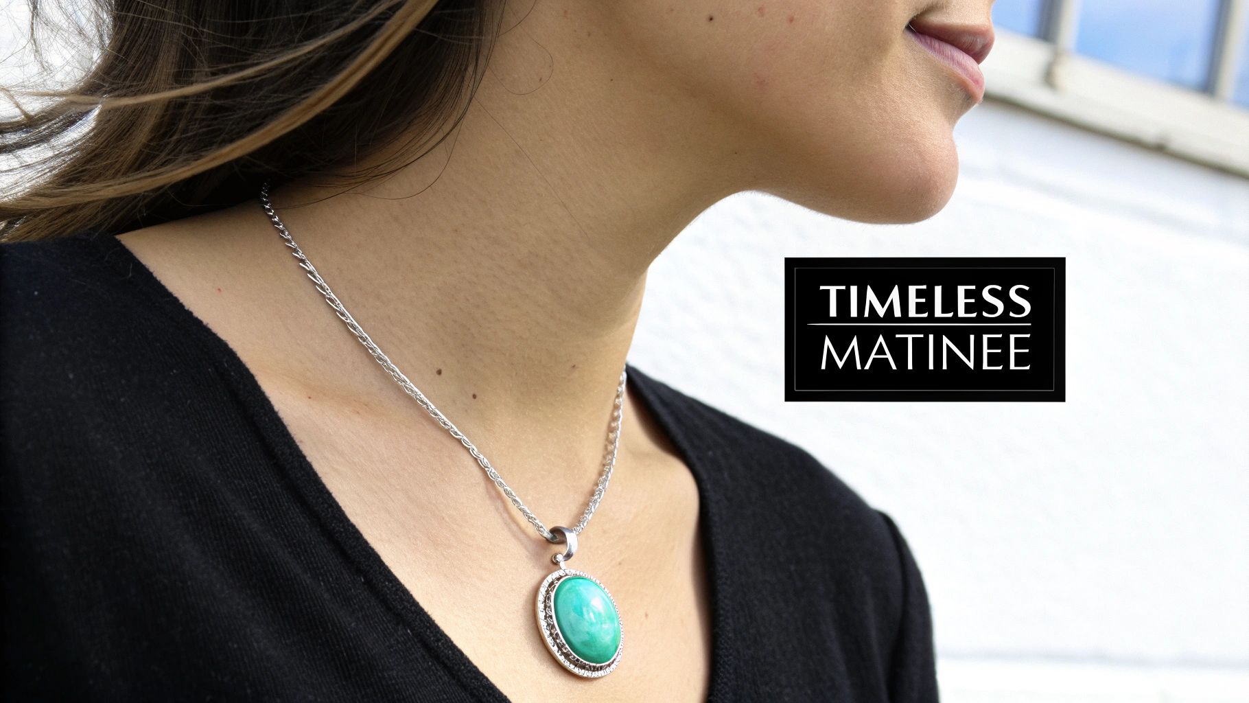A woman wears a stylish silver chain necklace with a vibrant oval turquoise pendant.