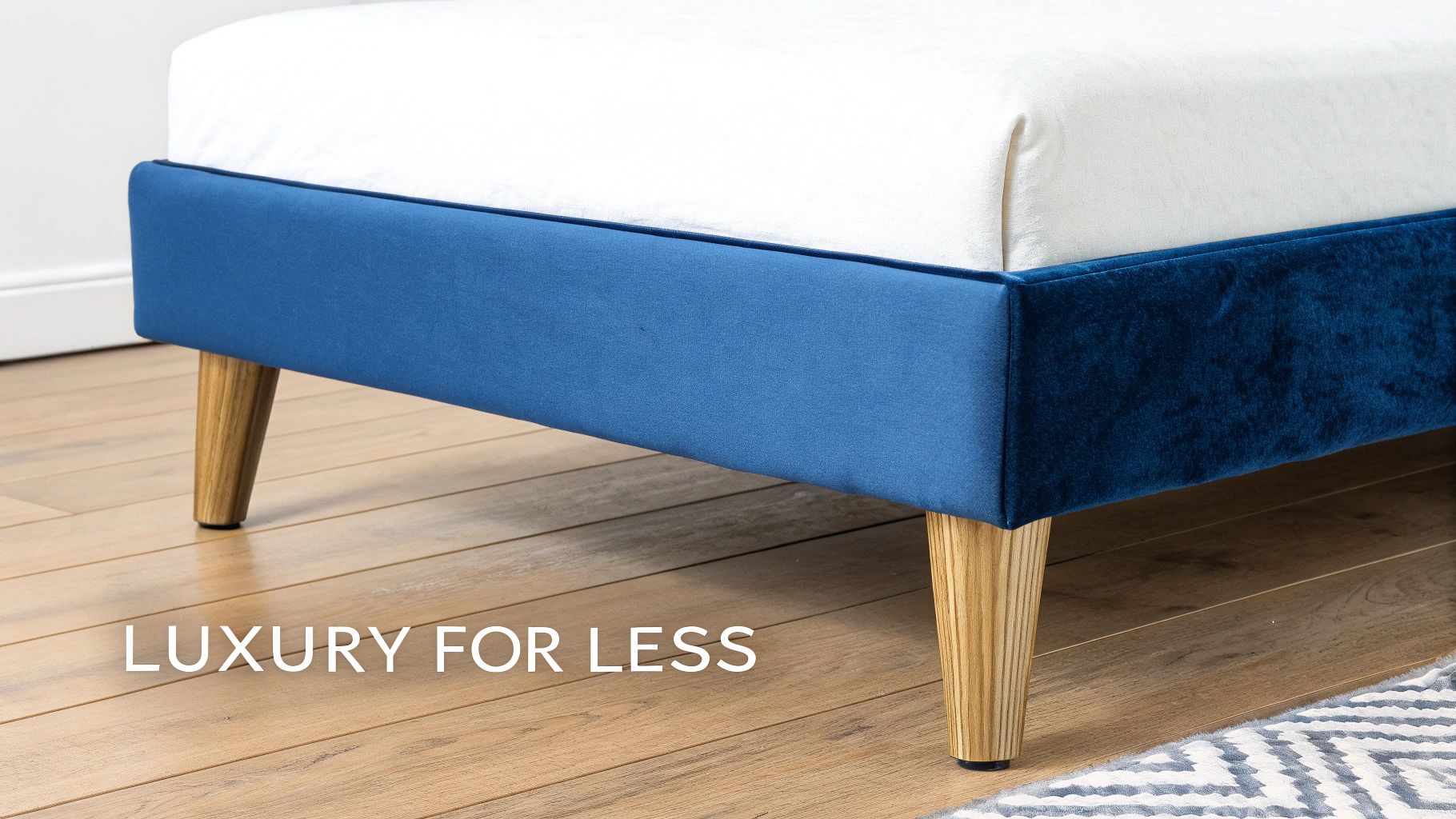 Stylish blue velvet and fabric bed base with tapered wooden legs in a bedroom setting.
