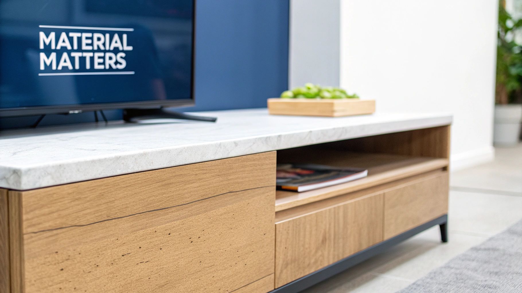 Modern media console with white marble top, wooden drawers, and a TV screen displaying 'MATERIAL MATTERS'.