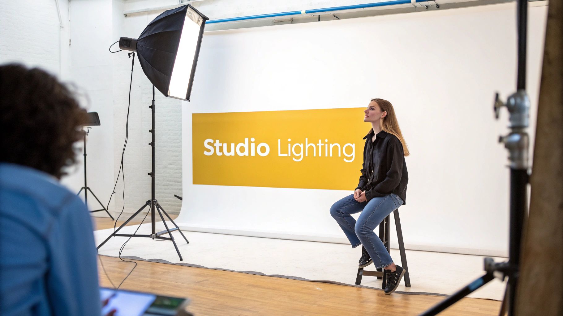 Woman posing on a stool in a photo studio with "Studio Lighting" backdrop and bright lights.