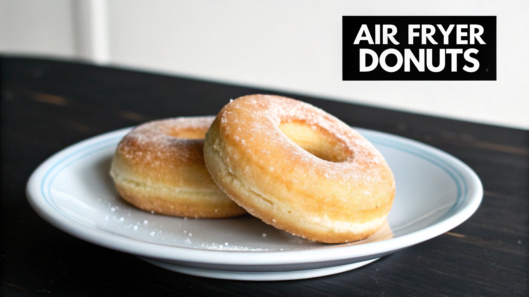 Two delicious air fryer donuts lightly dusted with powdered sugar on a white plate.