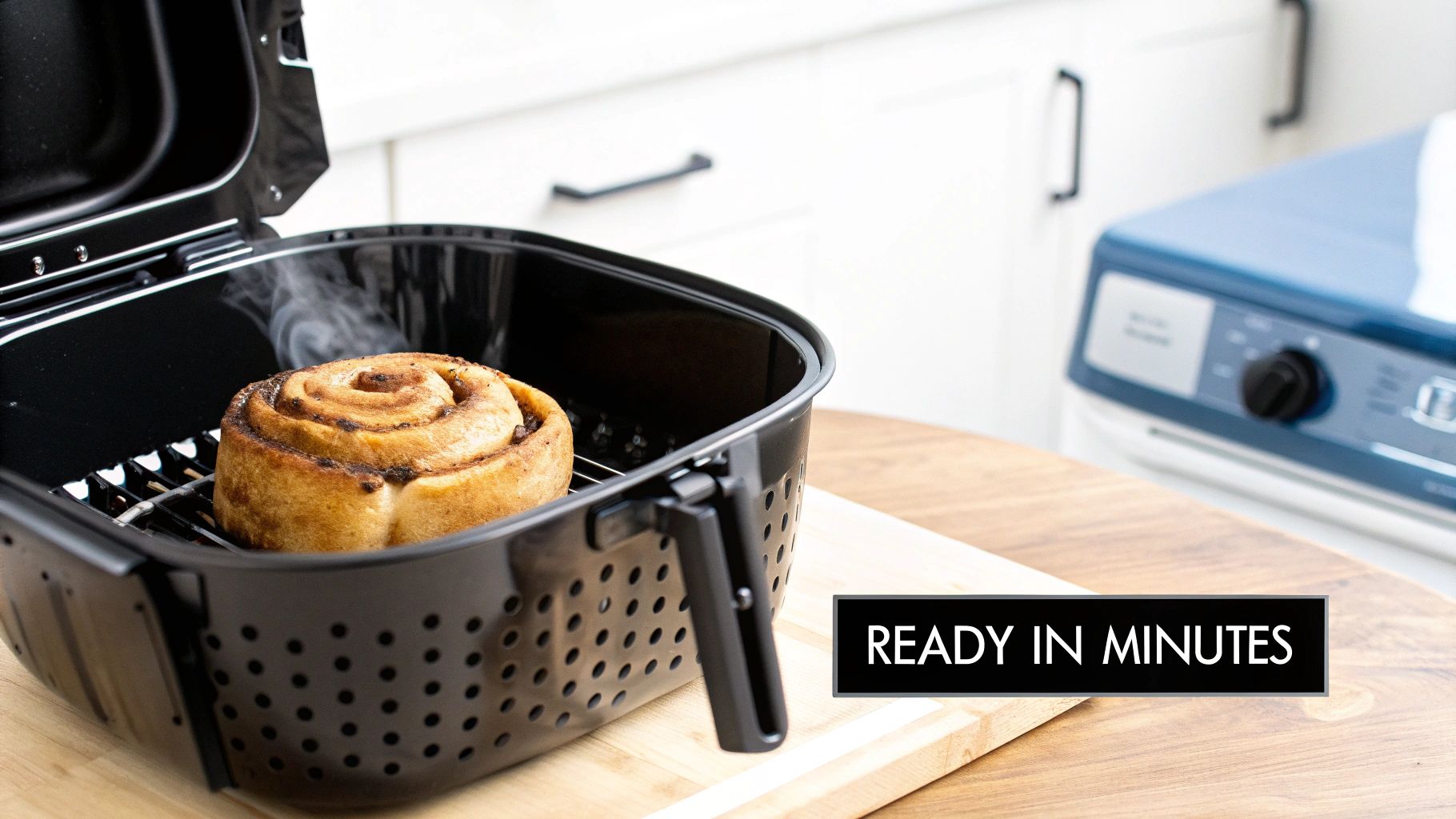 Cinnamon roll cooking in black air fryer basket on wooden countertop, ready in minutes