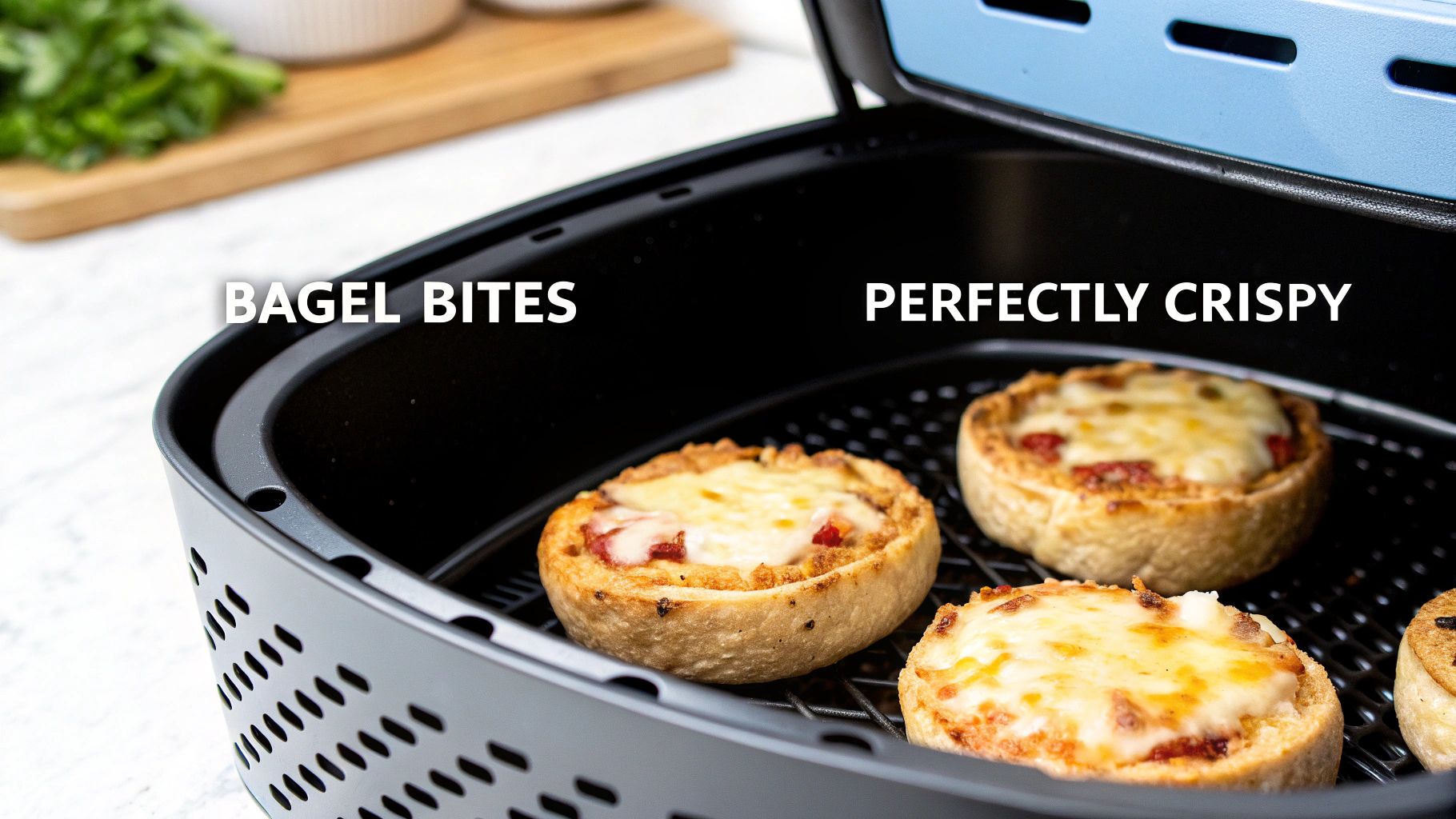 Mini bagel pizzas with melted, golden cheese cooking inside a black air fryer basket.