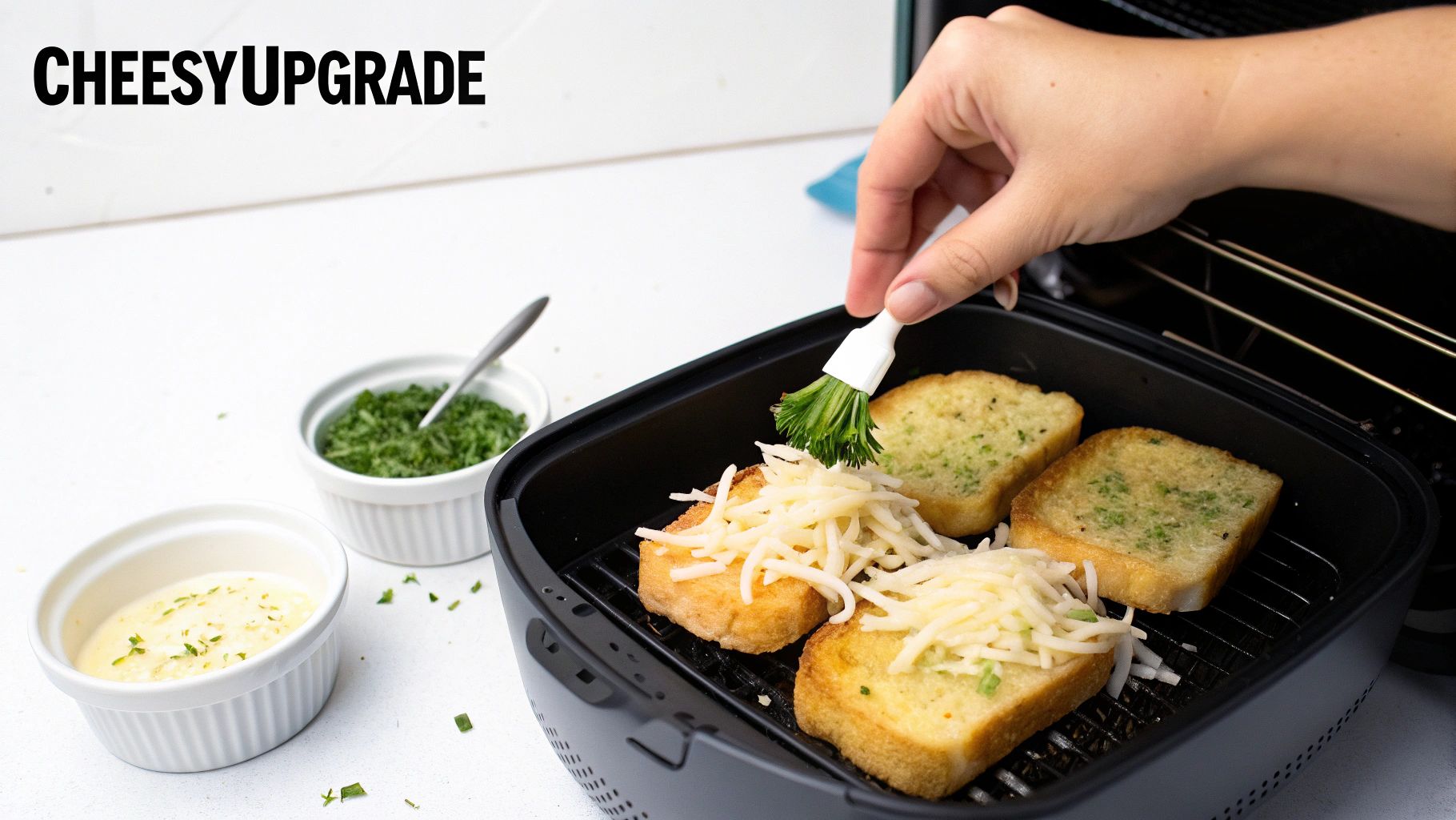 A hand brushes herbs onto cheesy garlic bread slices cooking in an air fryer basket.