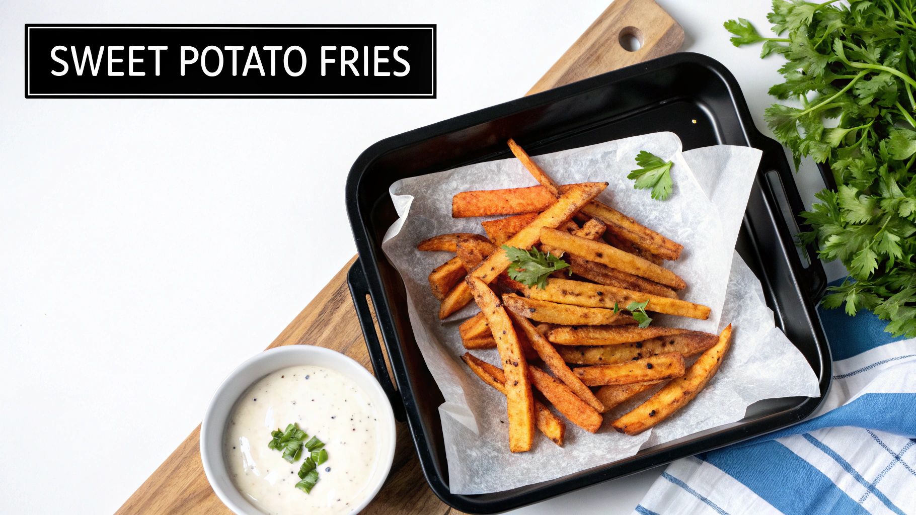 Crispy sweet potato fries served on a black baking sheet with a side of creamy dip and fresh parsley.