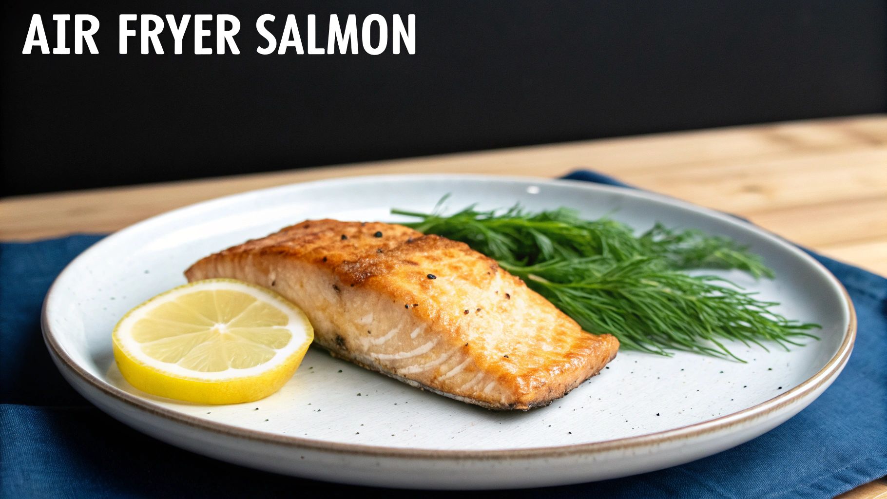 A perfectly cooked, golden-brown air fryer salmon fillet with a lemon slice and fresh dill on a white plate.