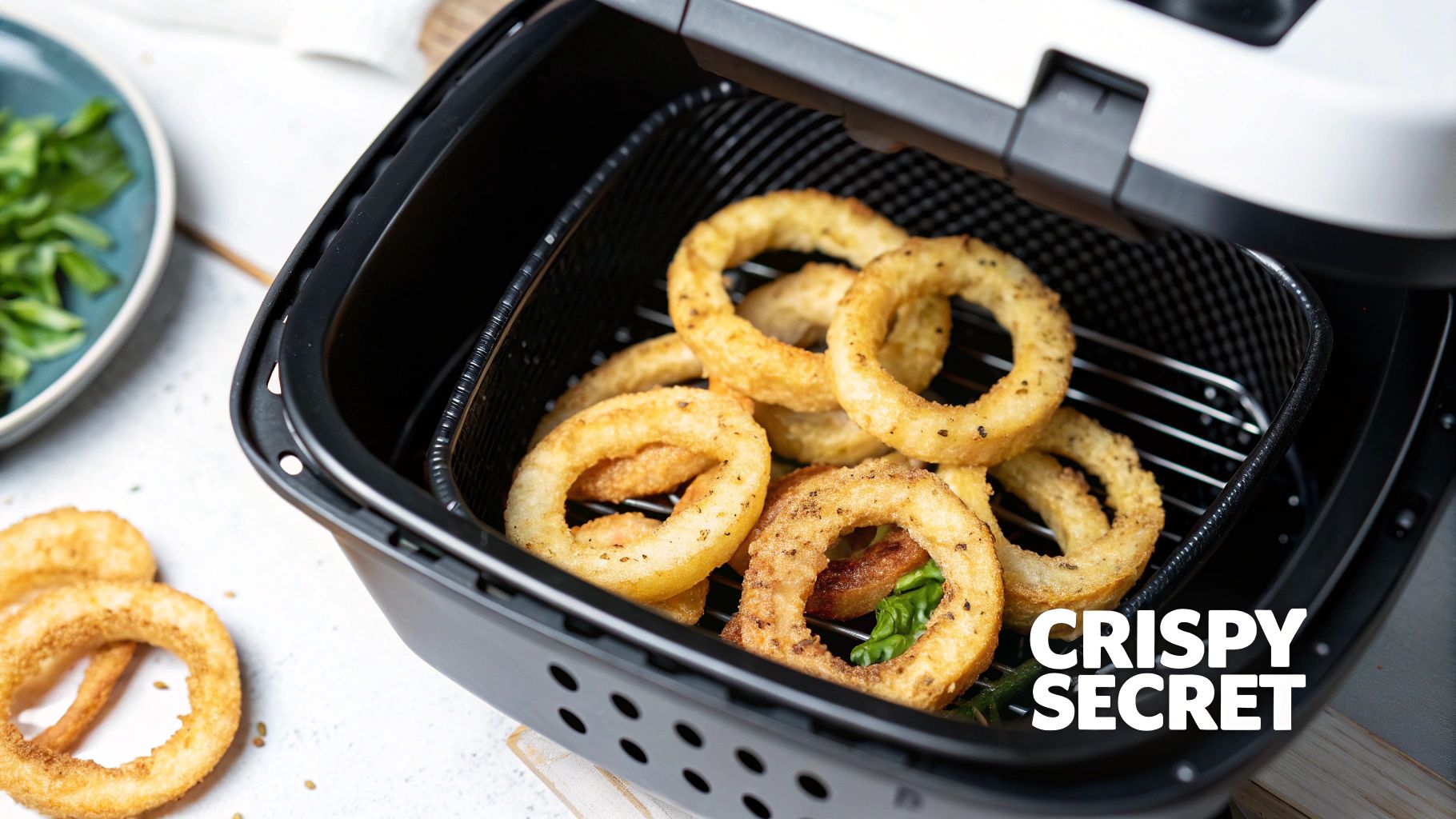 Crispy golden onion rings perfectly cooked in an air fryer basket, with green salad nearby.