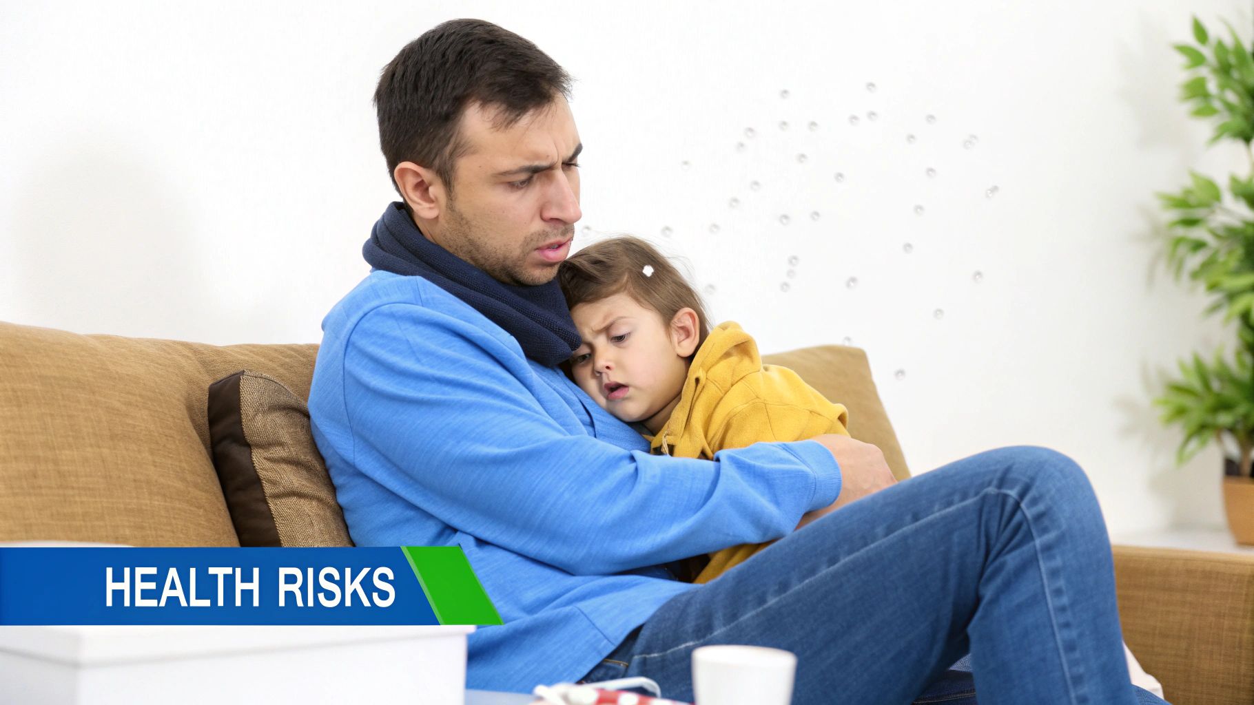 A concerned man in a scarf holds a sick young child, both appearing unwell on a couch.