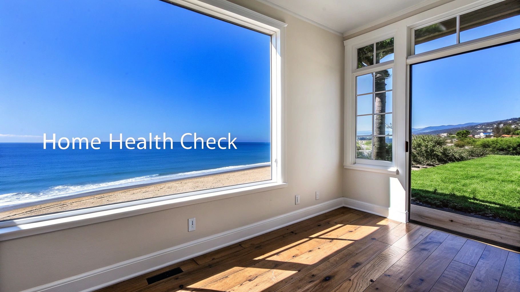 A bright room with a large window offering a stunning view of a beach and ocean, and an open door to a green backyard.