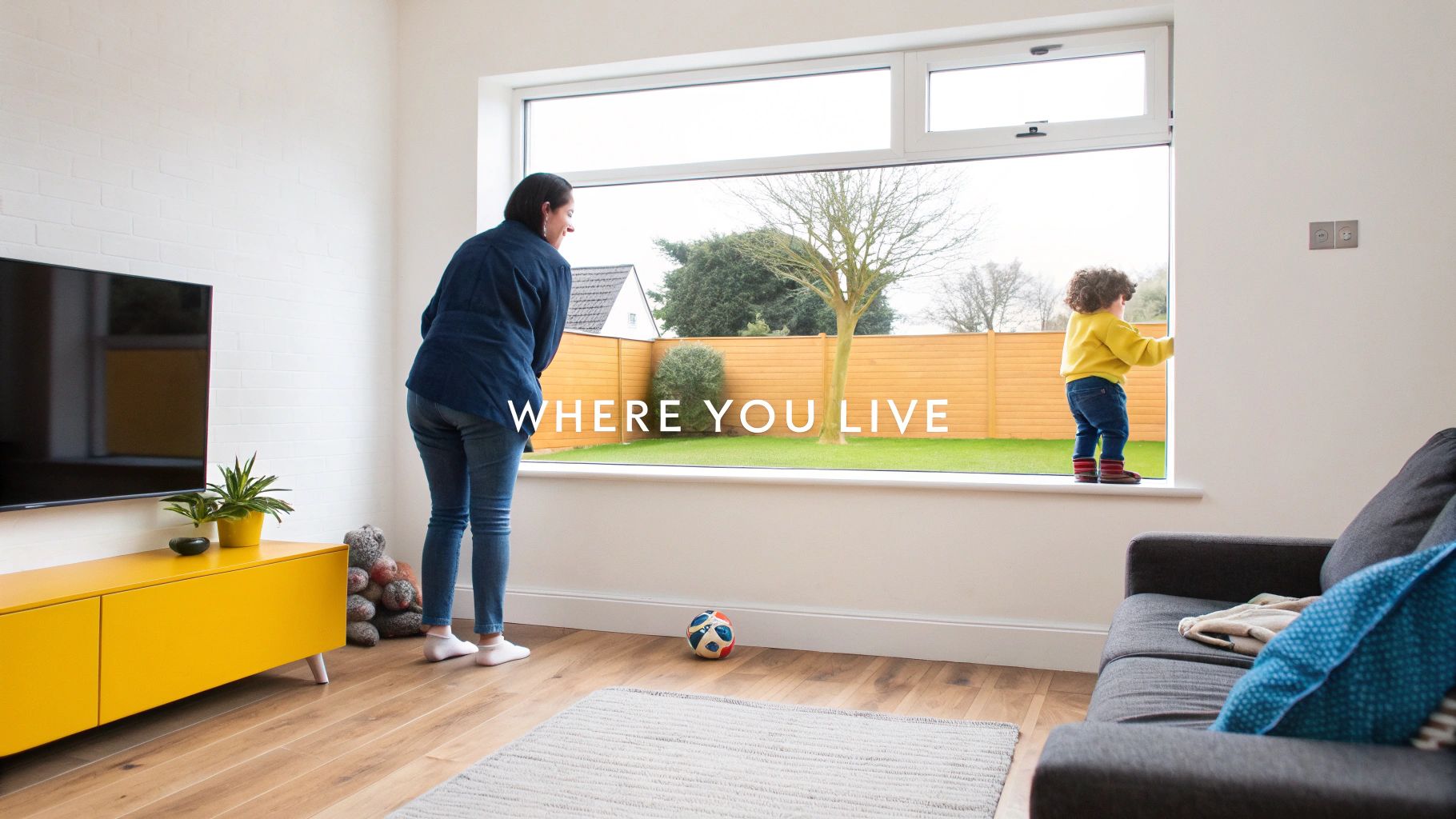 Mother and child looking through large window at backyard garden in modern living room