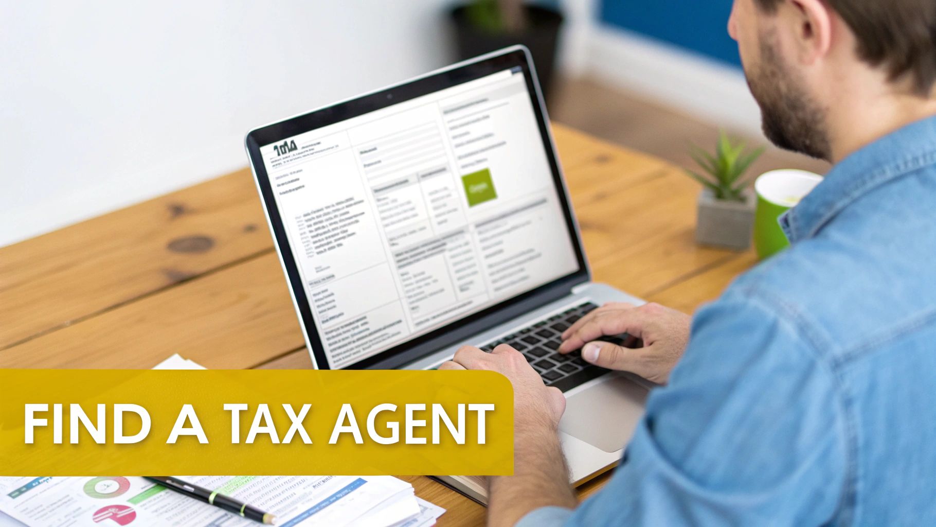 A man in a denim shirt types on a laptop, searching for a tax agent online.