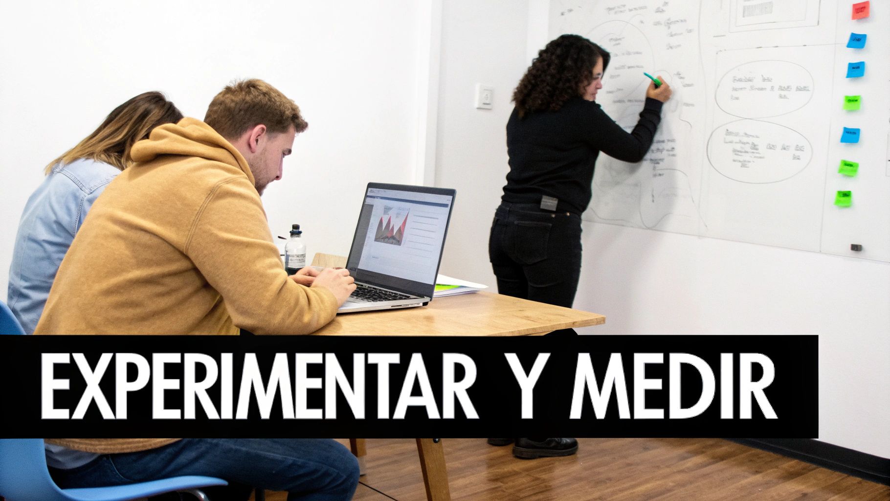 Equipo de trabajo experimentando y midiendo estrategias. Una persona escribe en pizarra, otra usa laptop.