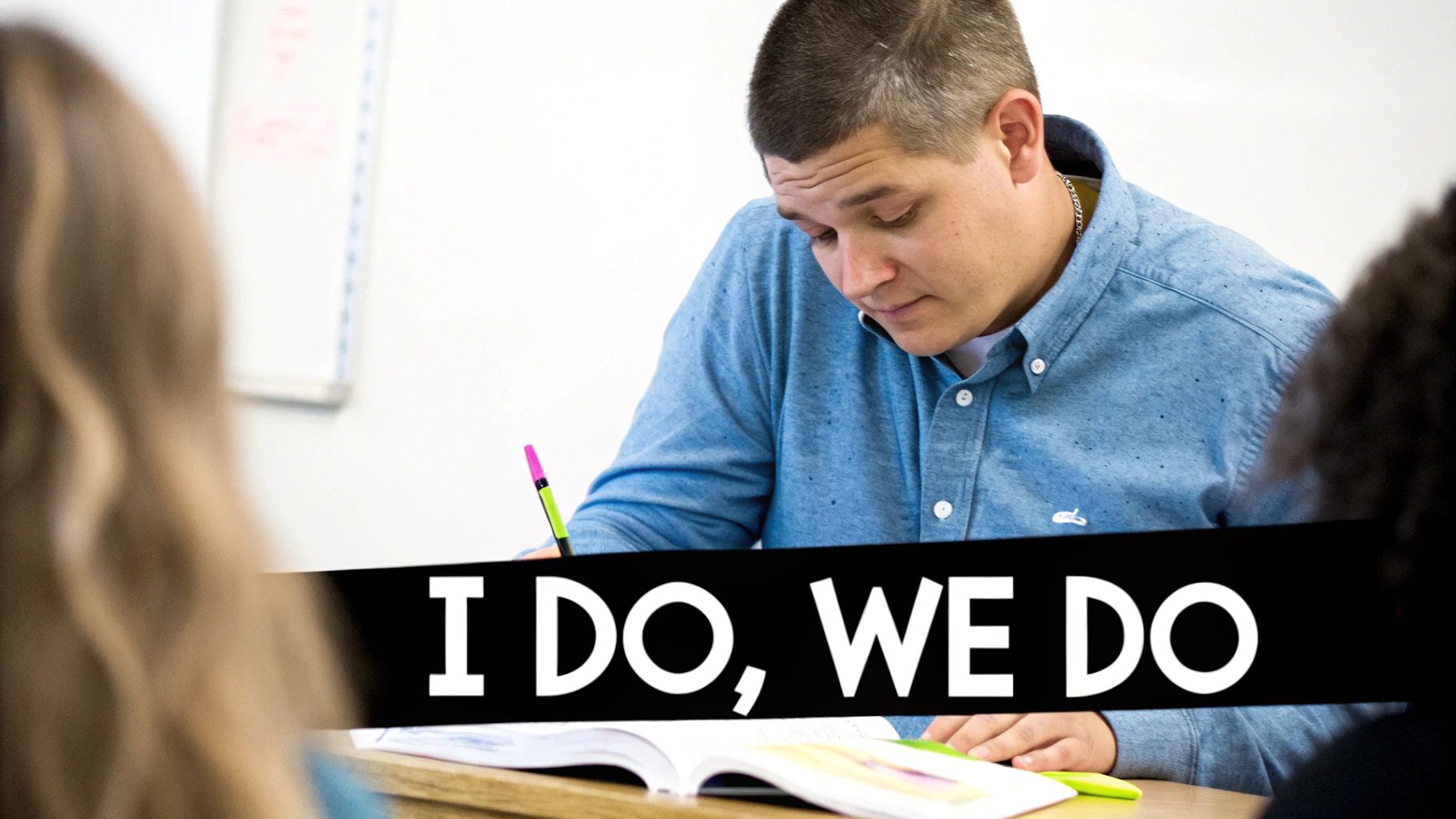 A man in a blue shirt diligently writes in a book on a desk, engaged in classroom learning.