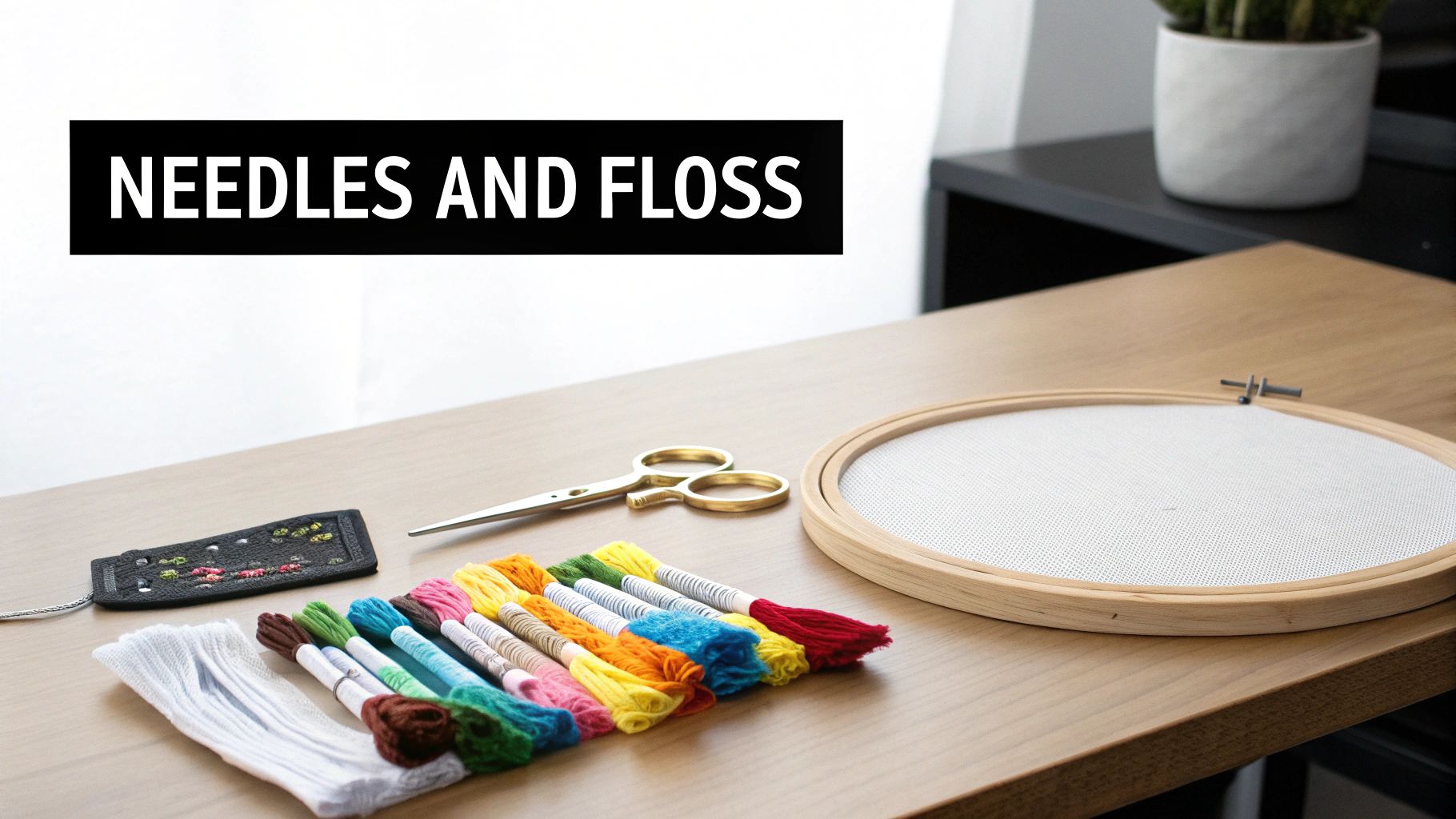 A flat lay of embroidery supplies including colorful floss, gold scissors, and aida cloth in a hoop.