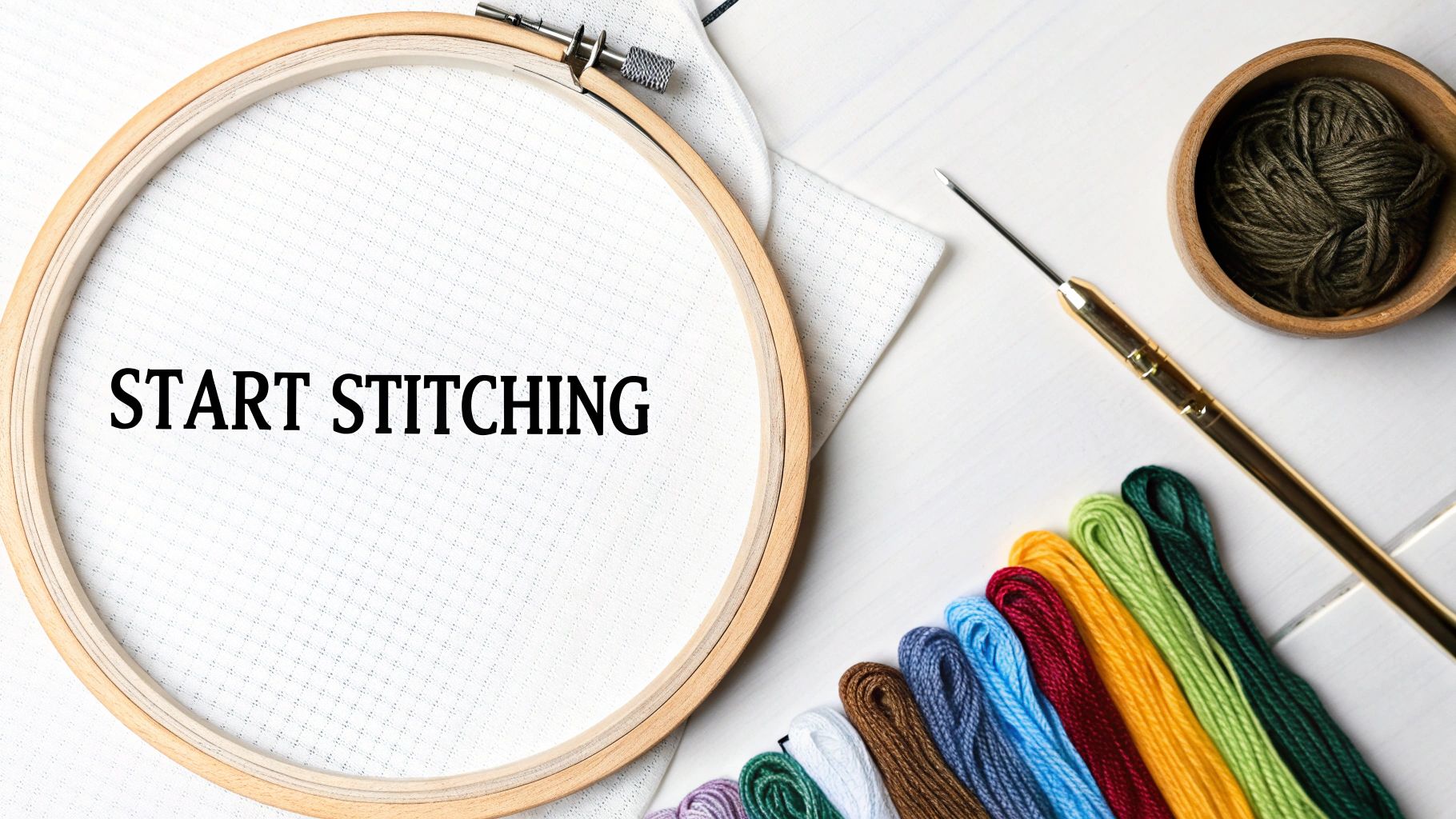 A flat lay of cross-stitching supplies including a hoop with "START STITCHING" text, colorful threads, and a punch needle.