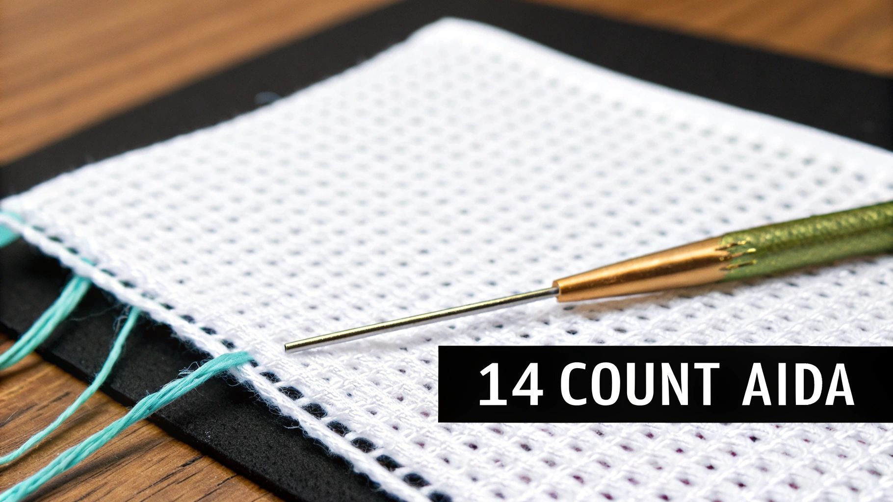 A close-up of a cross-stitch project on 14 count Aida cloth, showing the distinct grid pattern of the fabric with colorful threads.