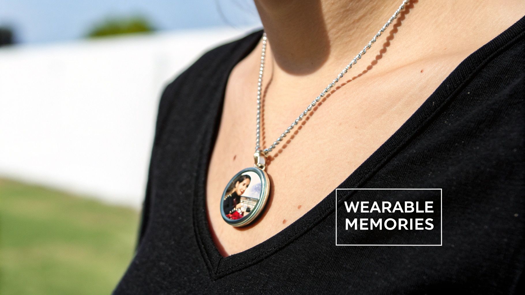 A person wears a silver necklace with a round custom photo locket, a wearable memory.