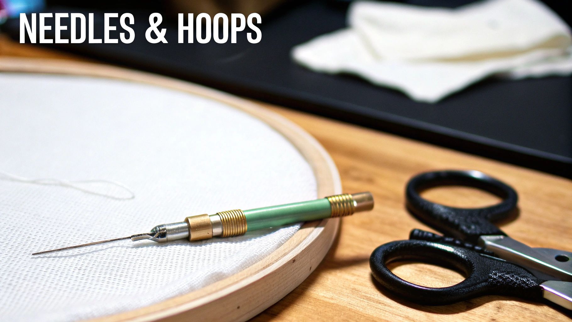 Close-up of embroidery supplies: a punch needle on white fabric in a hoop, with scissors.
