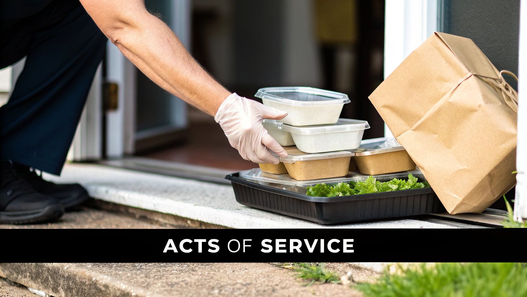 A gloved hand delivers a tray of pre-packaged meals and a brown paper bag to a doorstep.