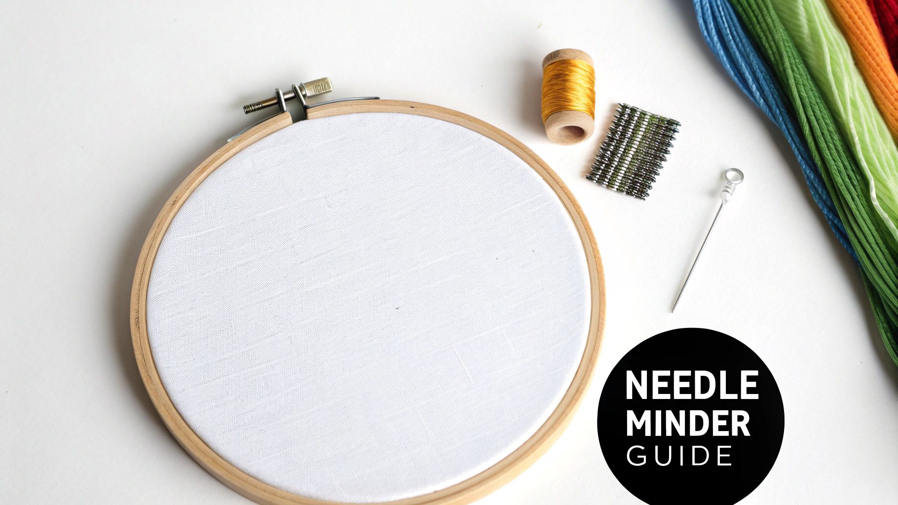 Overhead shot of cross stitch and embroidery supplies, including a hoop, thread, and needle minder.