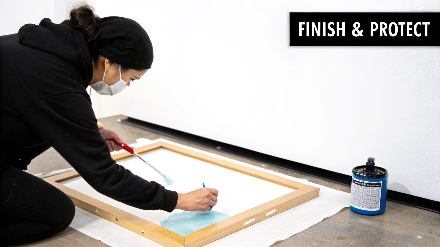 A person applying varnish with a brush to a finished canvas painting of a landscape.