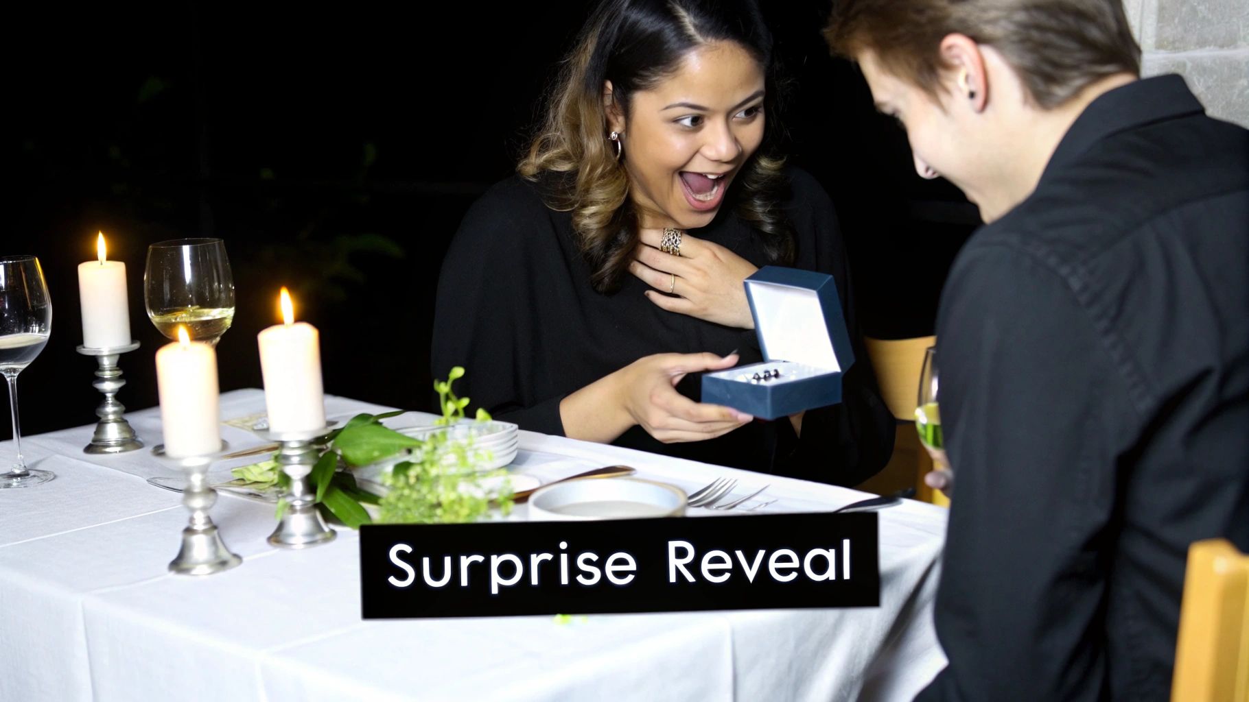 A woman shows delight as a man presents a small gift box during a romantic candlelit dinner.