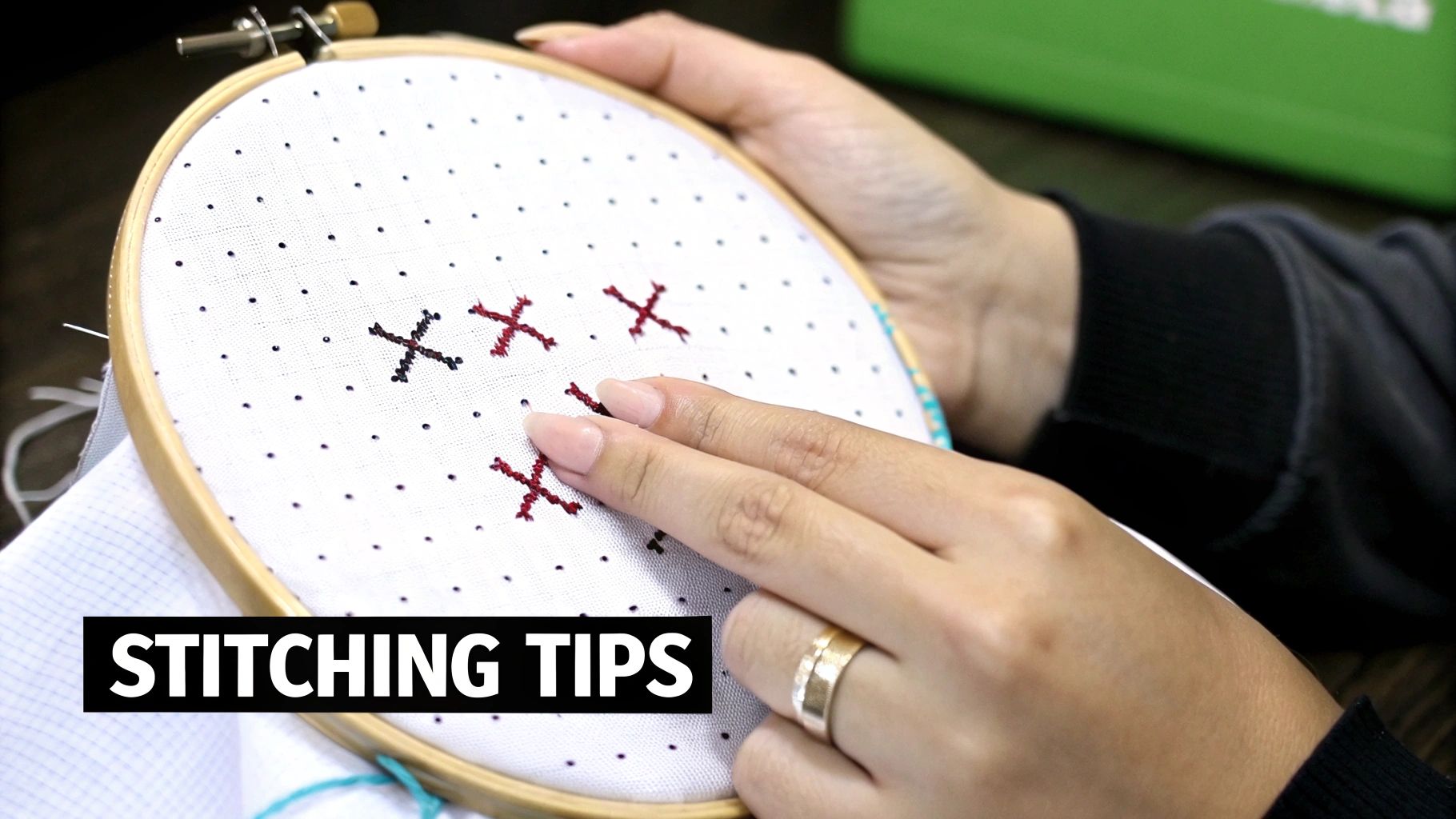 Hands hold an embroidery hoop with white fabric showing black and red cross-stitch patterns, with 'STITCHING TIPS' text.