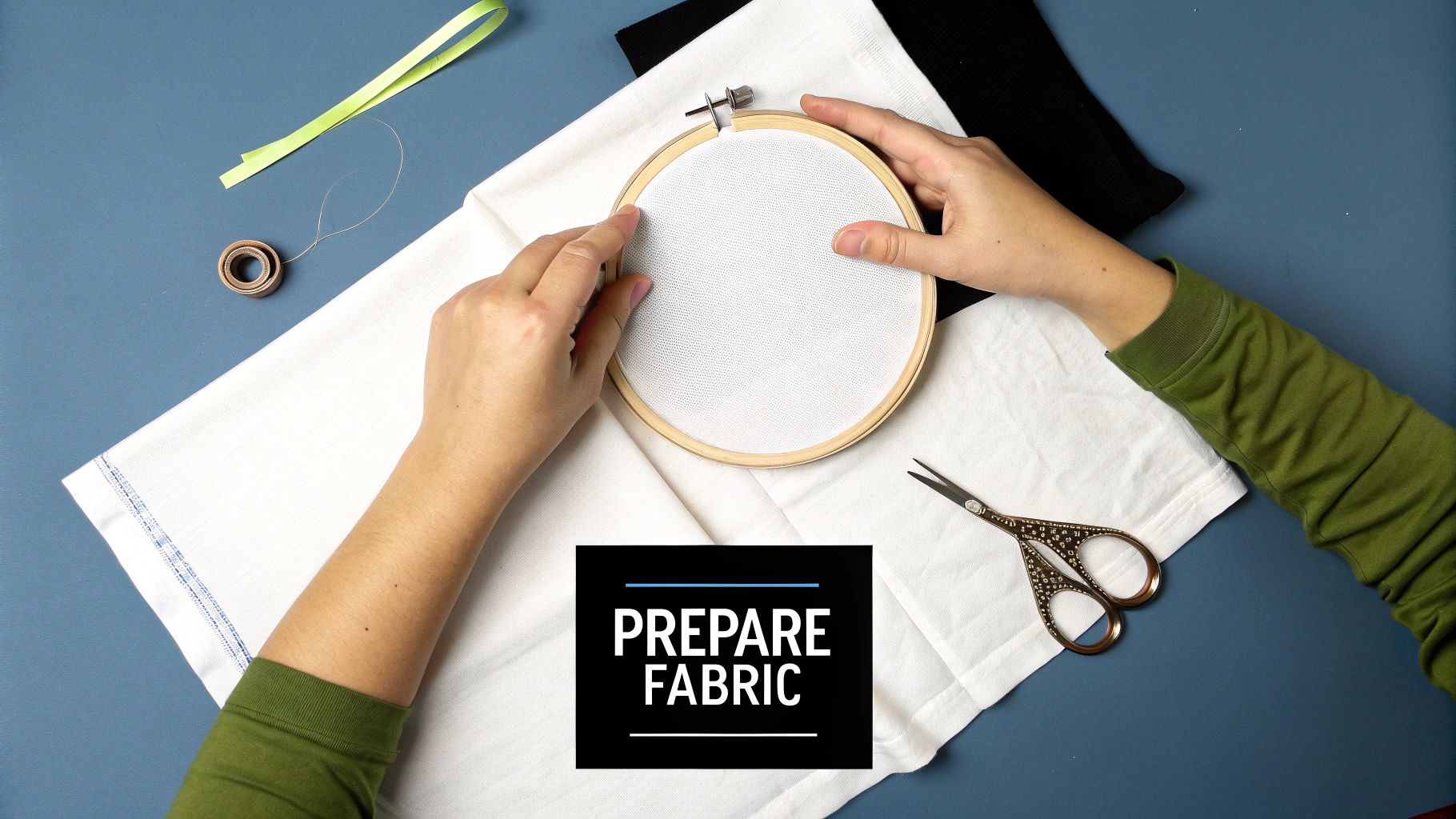 A person's hands stretch white fabric onto a wooden embroidery hoop, preparing for cross stitch.