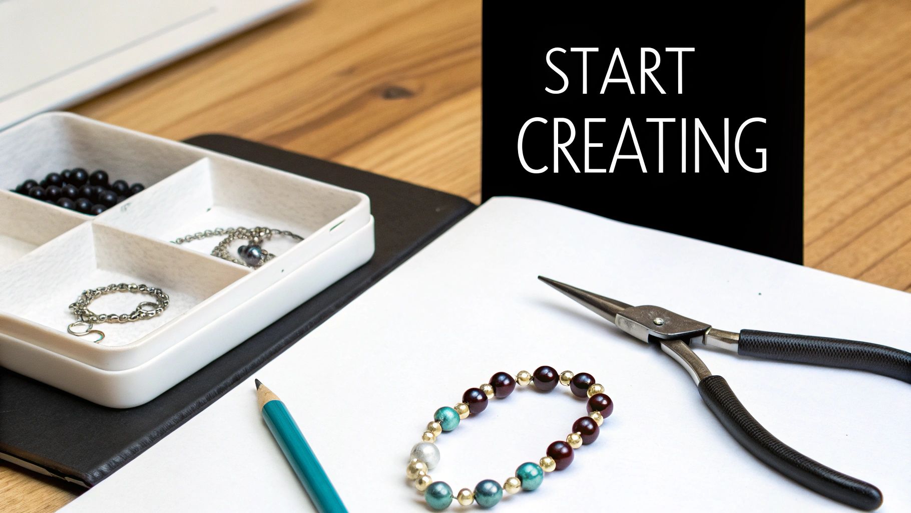 Jewelry making tools and supplies on a wooden desk with a 'Start Creating' sign, inspiring creativity.