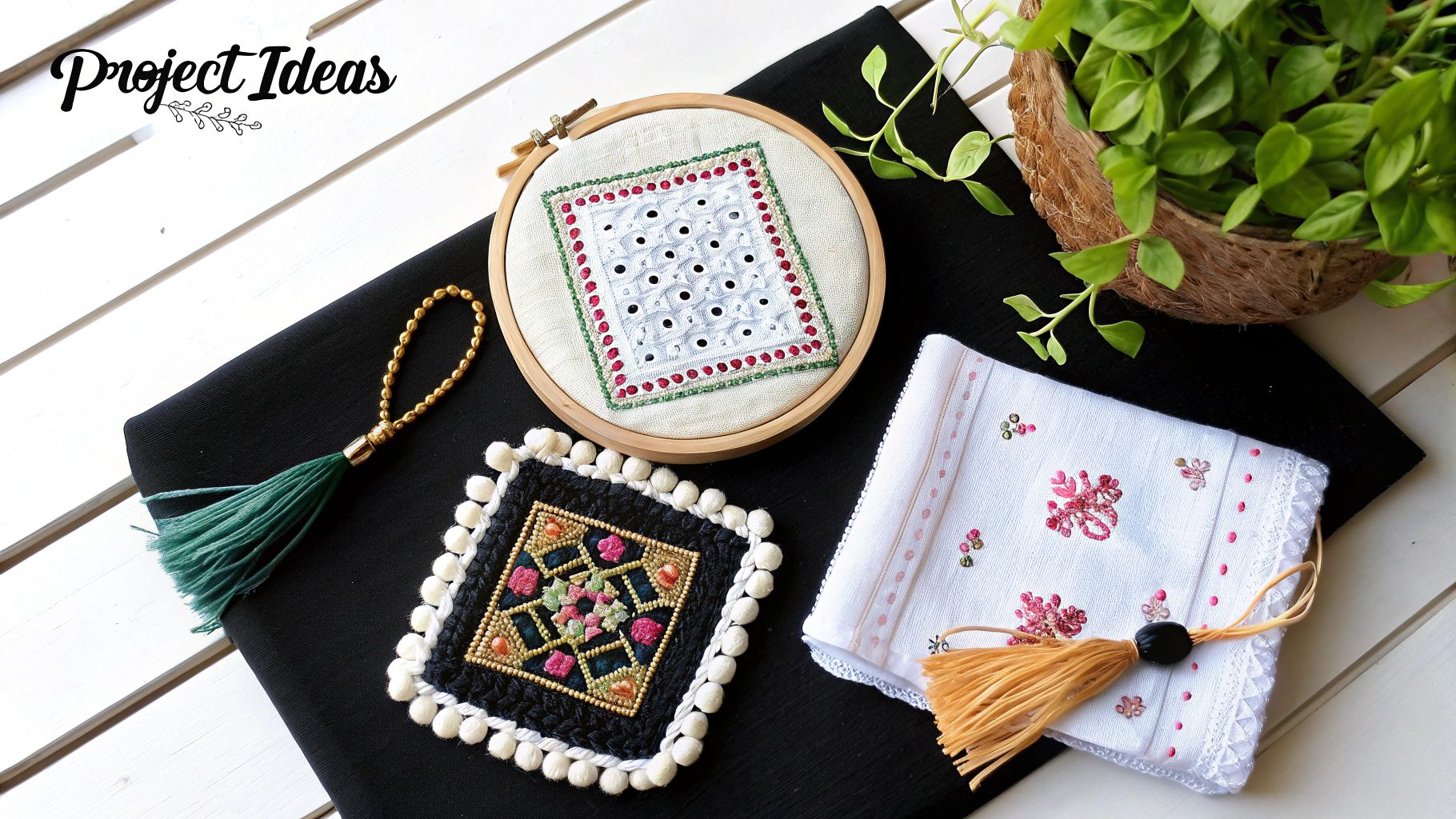 Overhead view of various colorful embroidery and beadwork craft projects on a black cloth and white wood table.