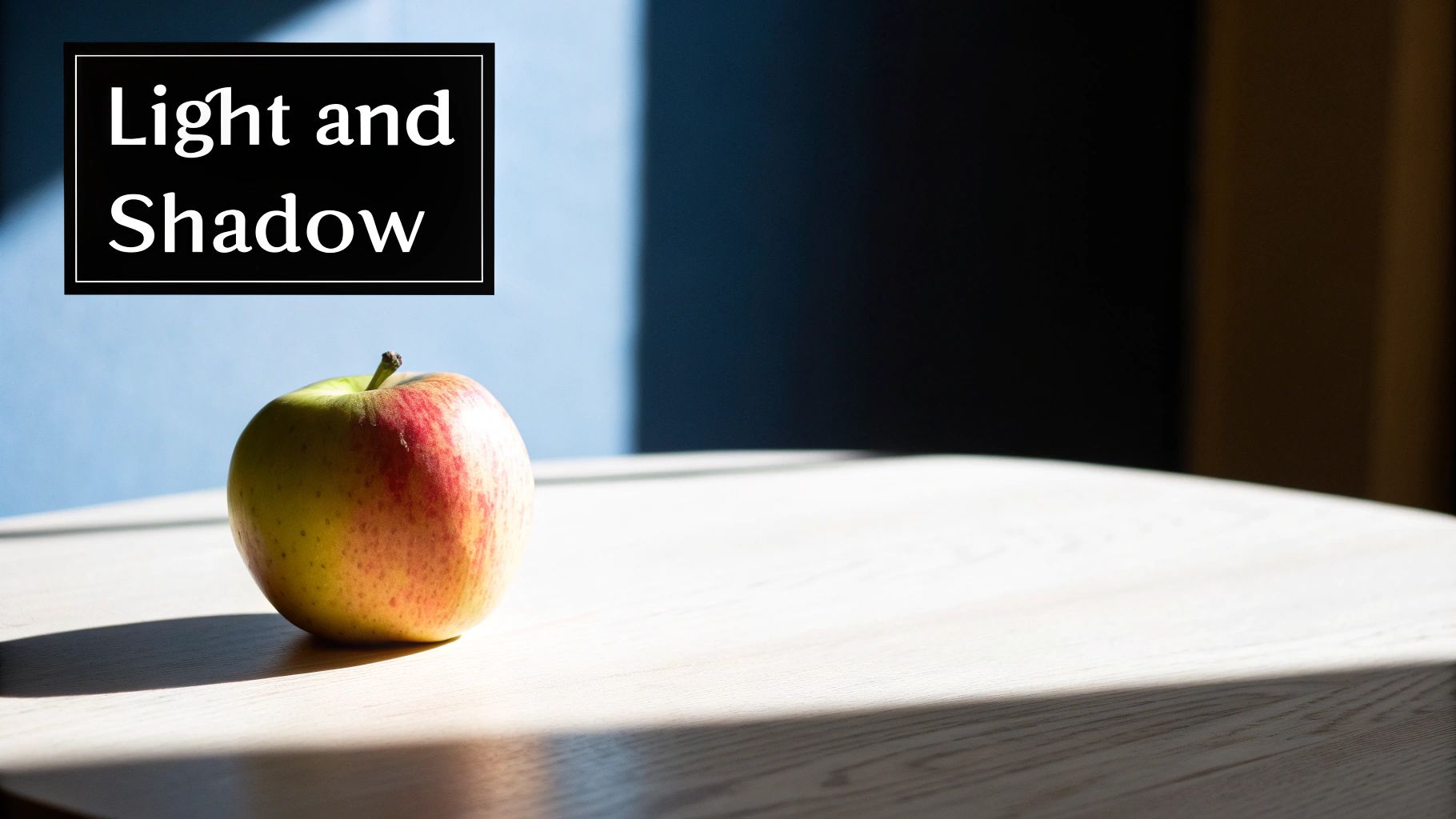 Apple with red and yellow tones on white surface demonstrating light and shadow contrast