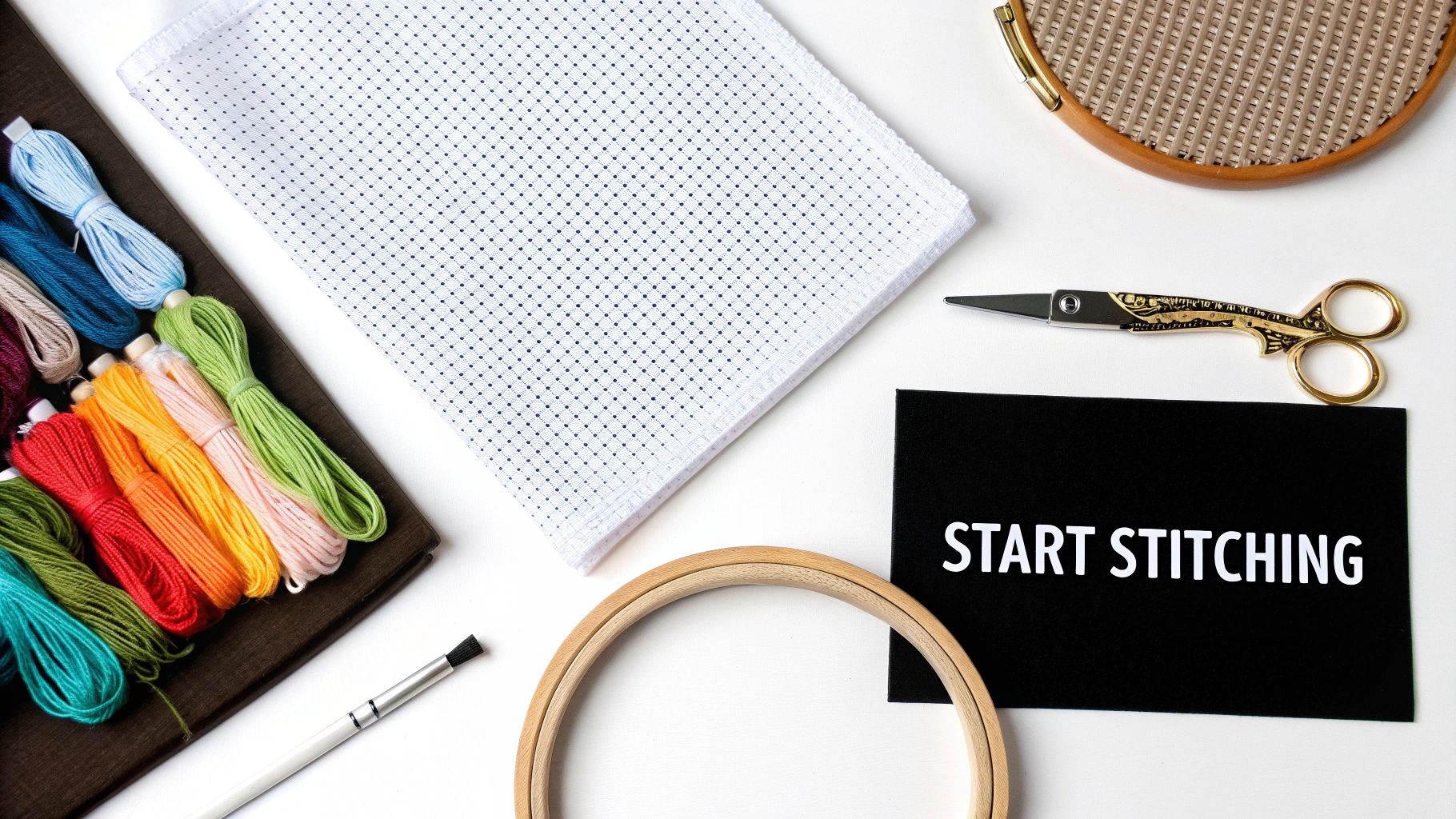 A colourful assortment of cross stitch supplies including fabric, thread, and scissors.