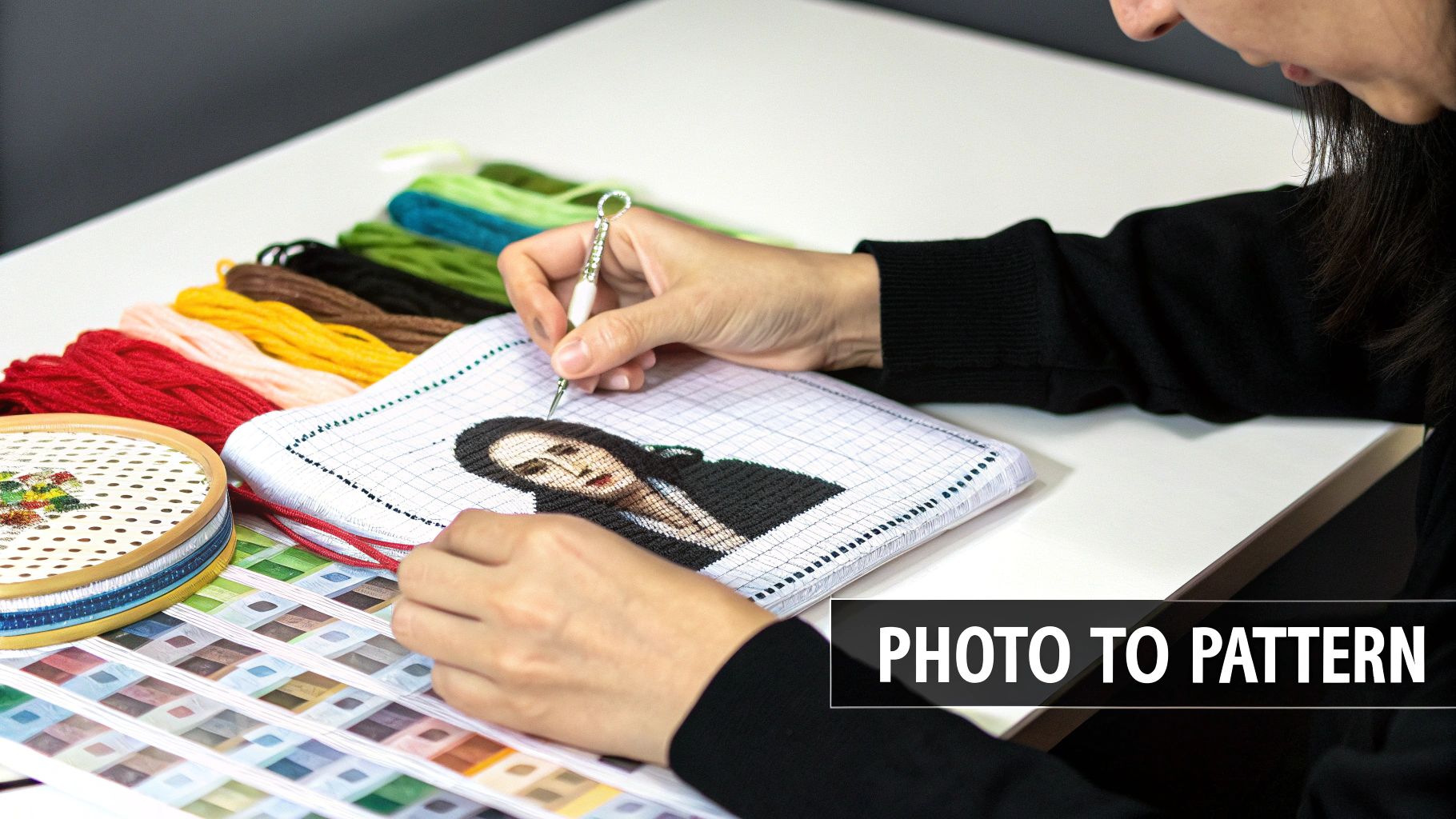 Hands embroidering a portrait on gridded fabric with colorful threads, hoop, and color chart nearby, demonstrating 'photo to pattern' craft.