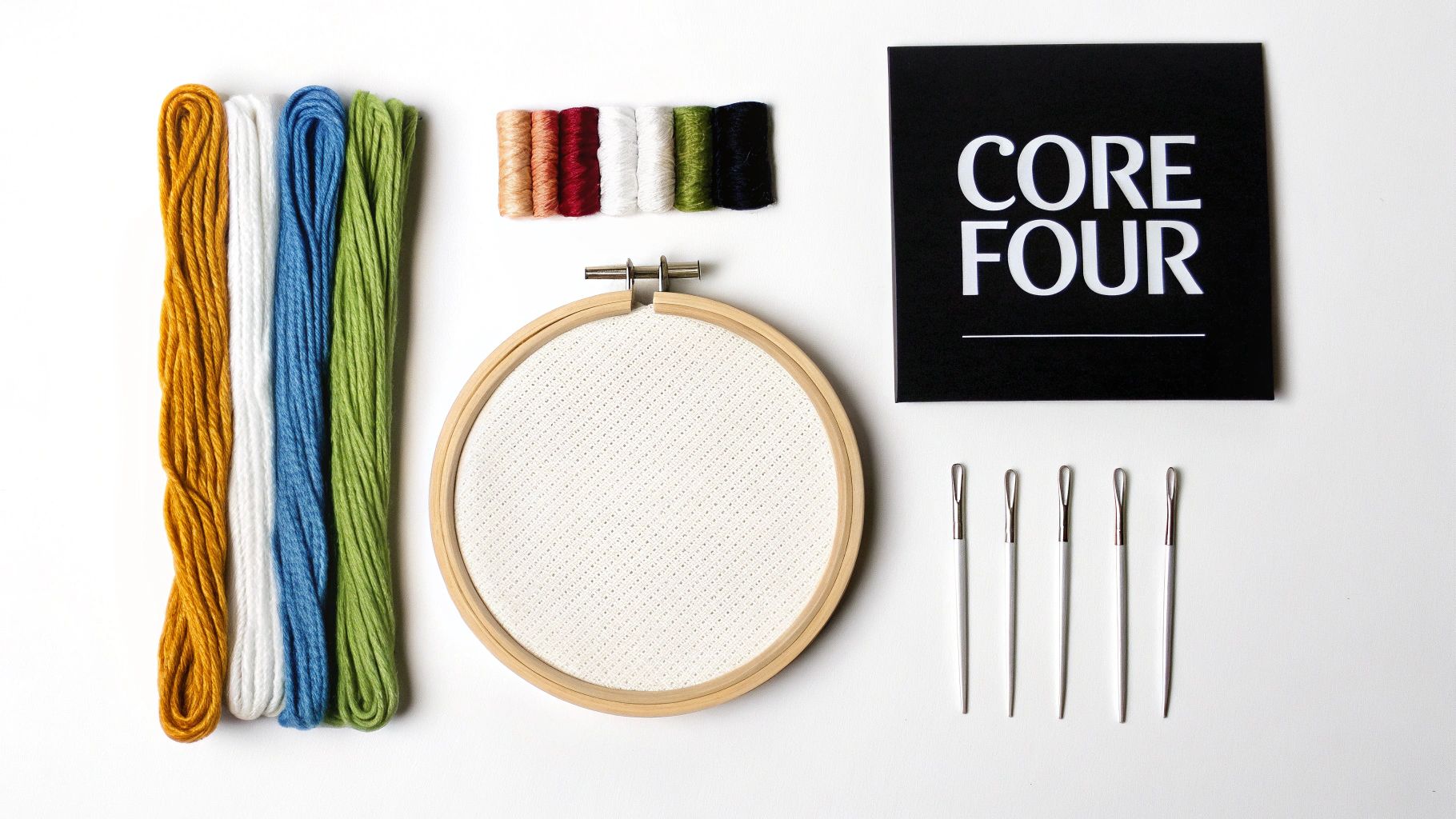 A flat lay of embroidery supplies including colorful floss, a wooden hoop with fabric, and needles.