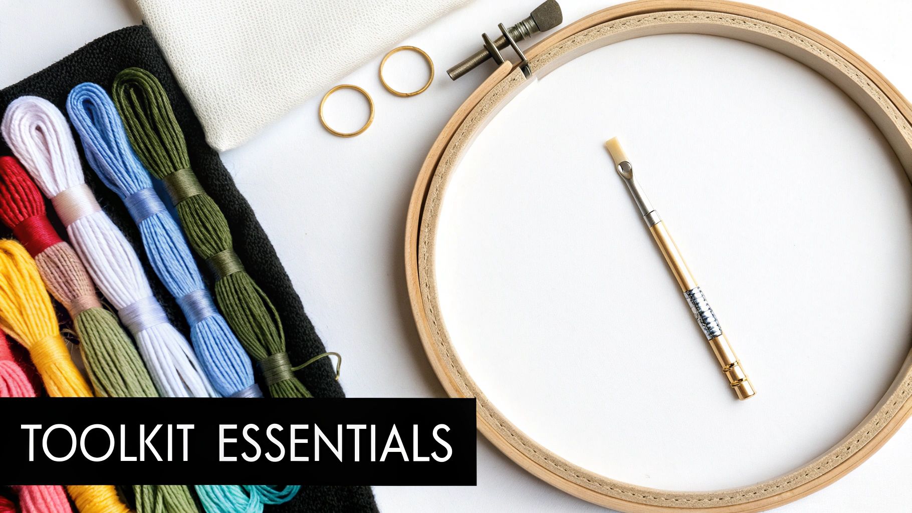 An organized flat lay of cross stitching supplies, including colorful threads, Aida fabric, an embroidery hoop, and needles.