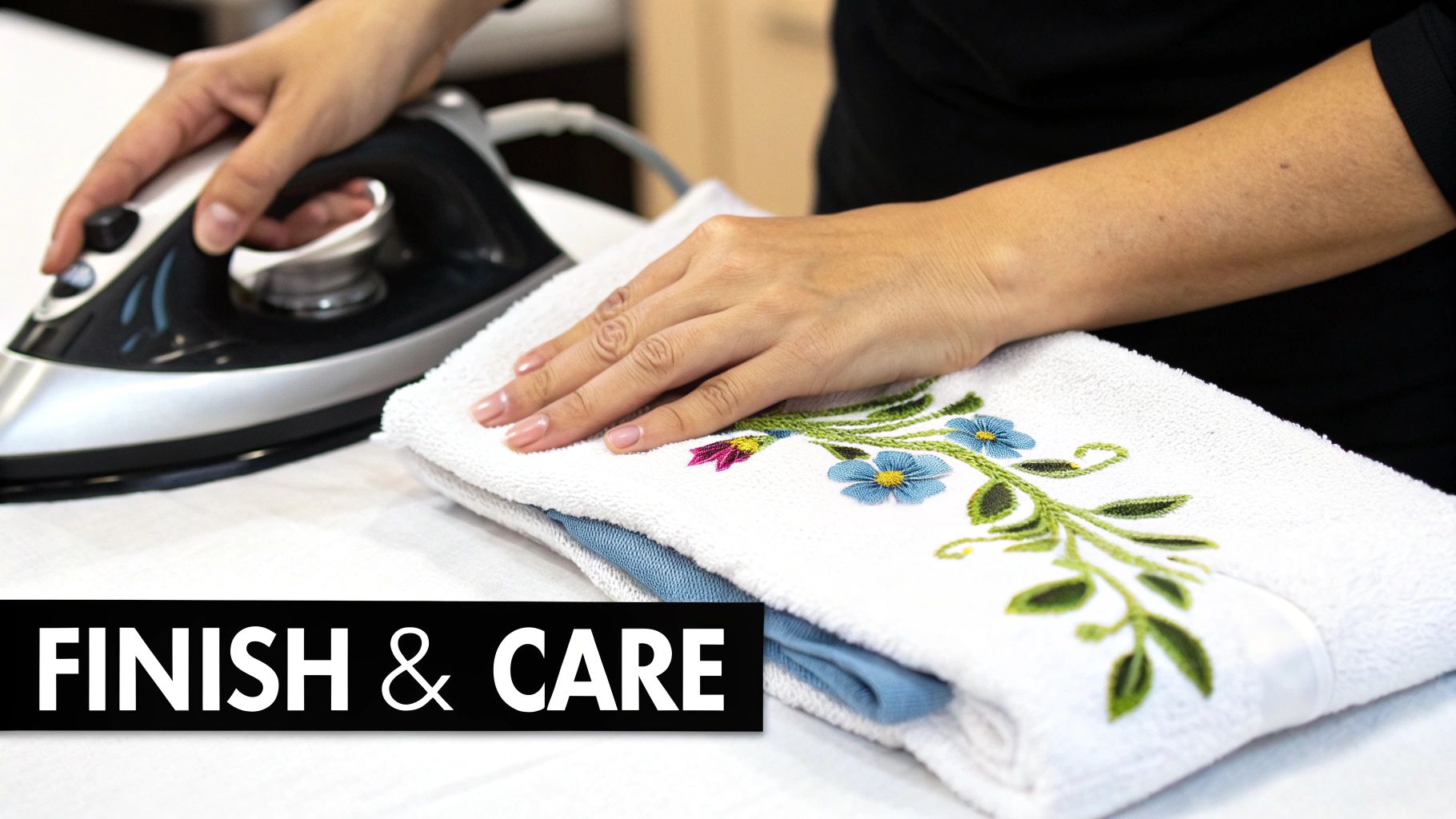A person's hands are shown ironing a white towel with blue and pink floral embroidery, with "FINISH & CARE" text.