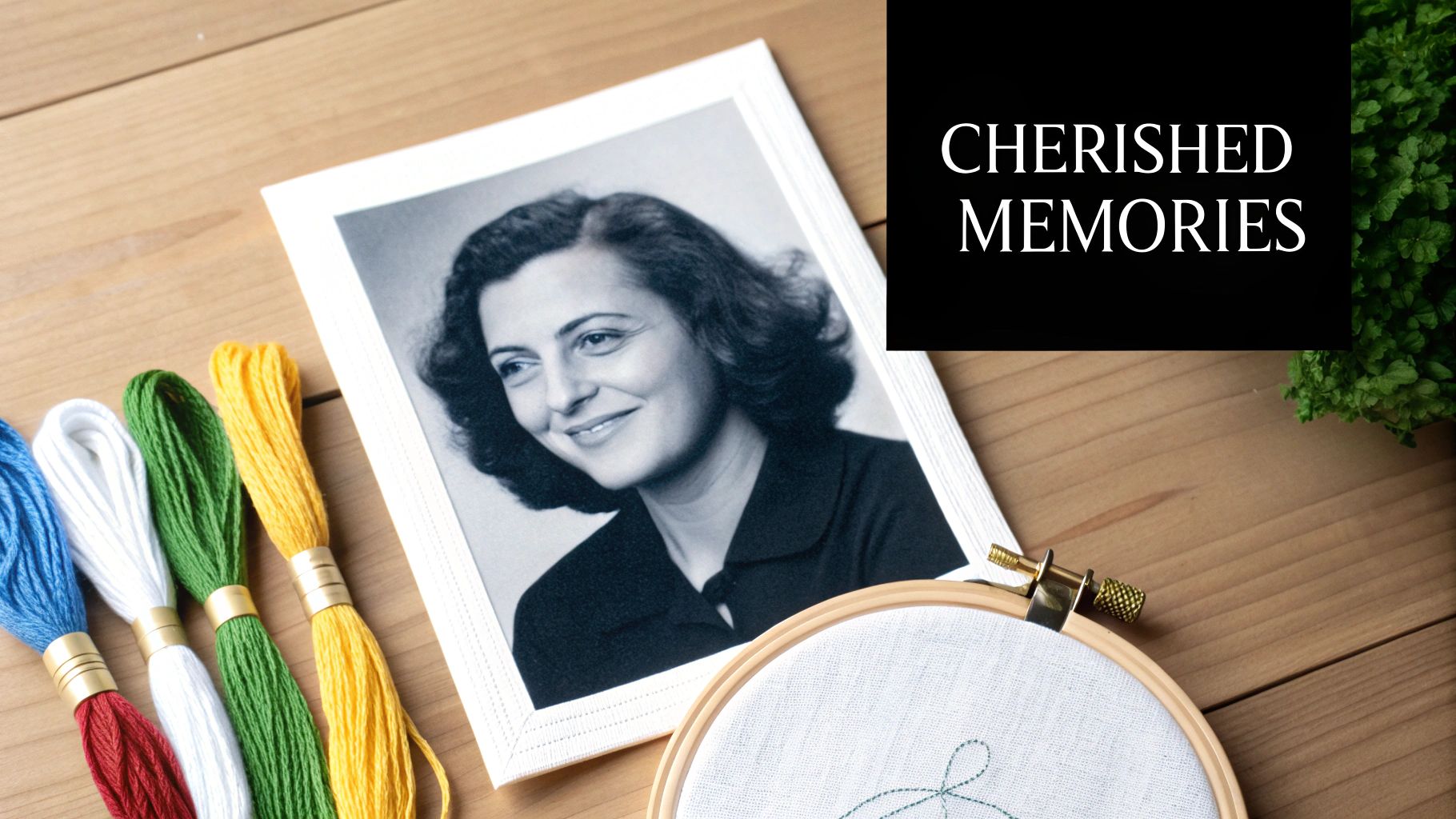 A framed black and white portrait of a smiling woman, colorful embroidery threads, and a hoop.