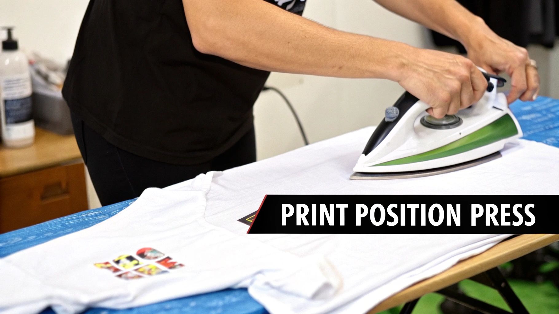 A person applying a textile transfer paper design to a white t-shirt with a heat press.