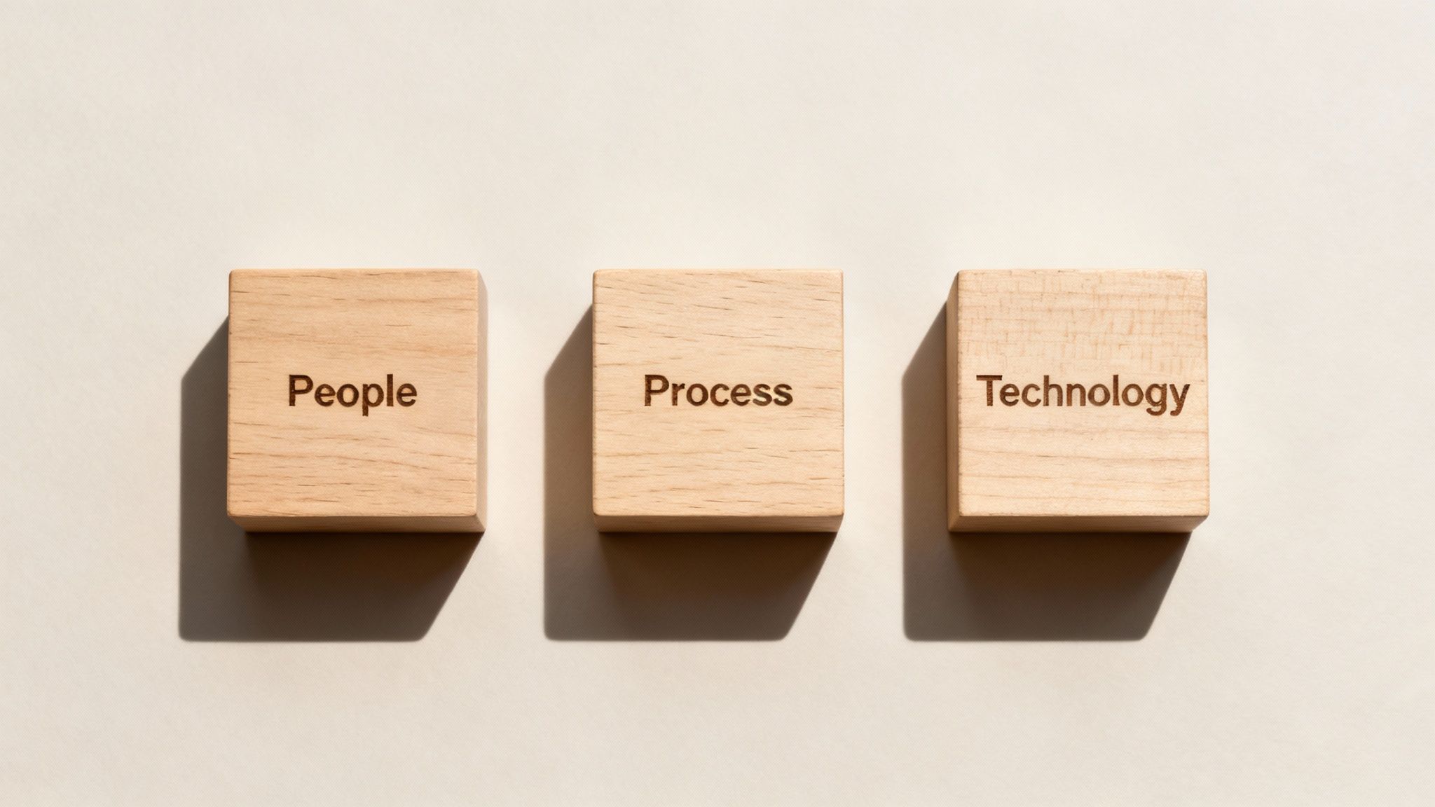 Three wooden blocks display 'People', 'Process', and 'Technology', representing essential business concepts.