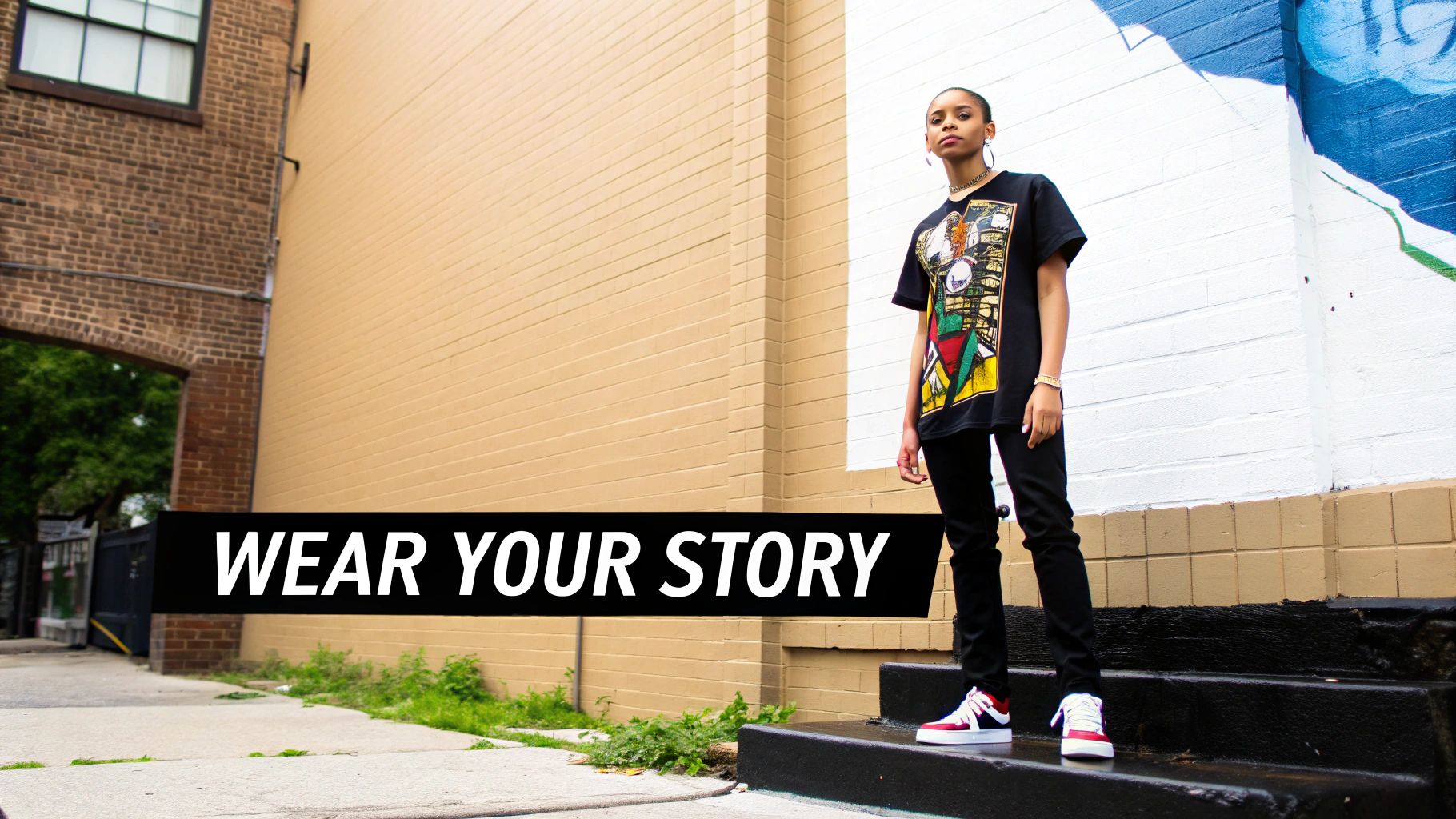 A young woman in a black graphic t-shirt and red and white sneakers stands on urban steps.